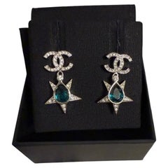 Pendientes colgantes CHANEL de cristal plateado con la inicial CC y una estrella de gemas verdes