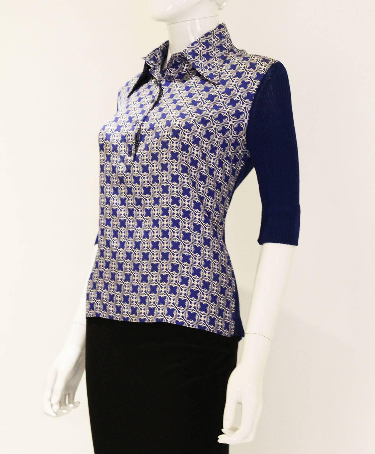A wonderful collared blouse by Hermes. In a lovely bright blue, the front and collar are in silk, and the back and elbow length sleeves are in a cotton knit. The blouse has all its original buttons, and there is a spare one inside.