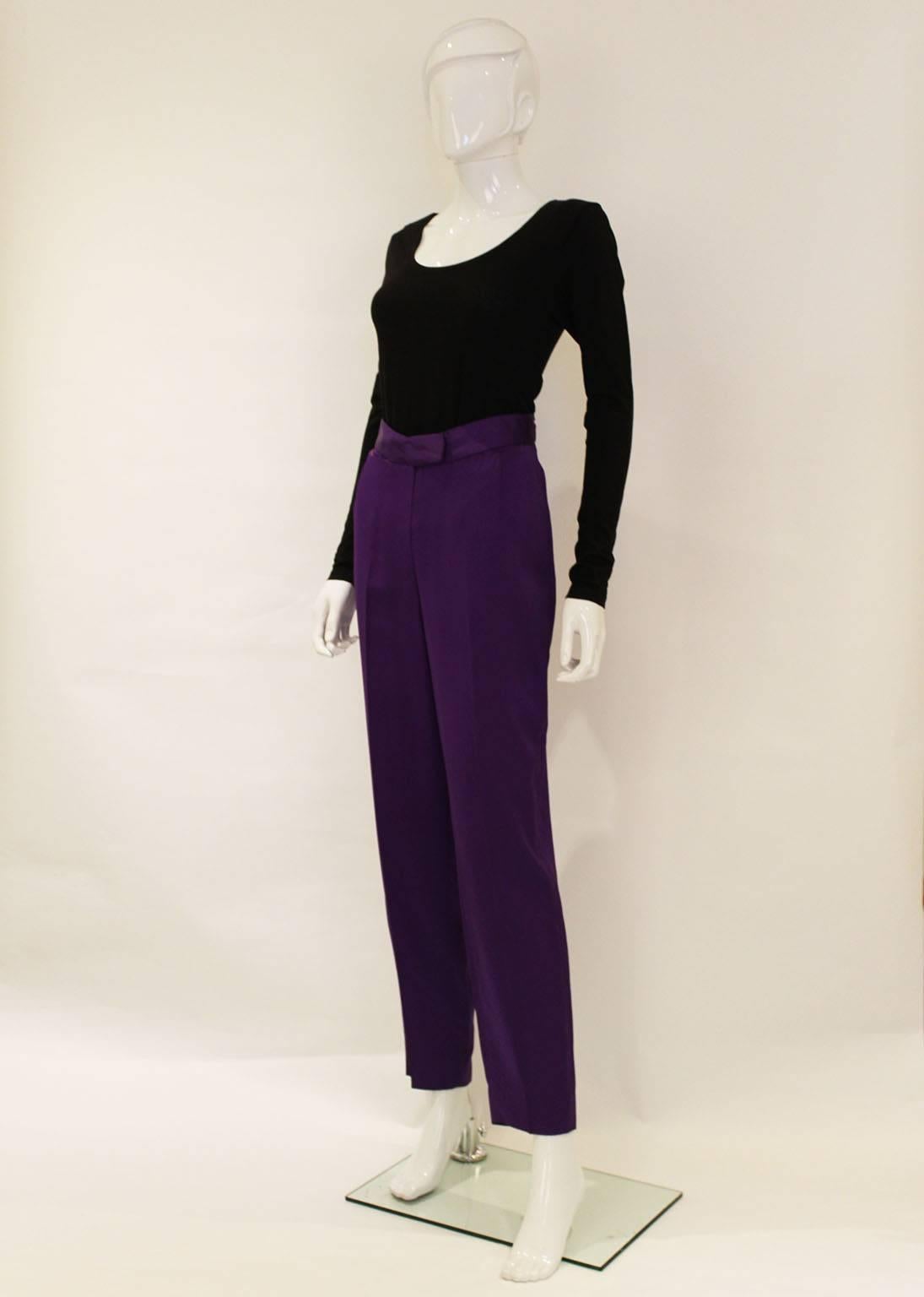 These trousers are a real head turner, in a regal purple colour and partly lined.
There is a central zip with a pocket on either side.The back of the waistband has a v shape and there is one back pocket.