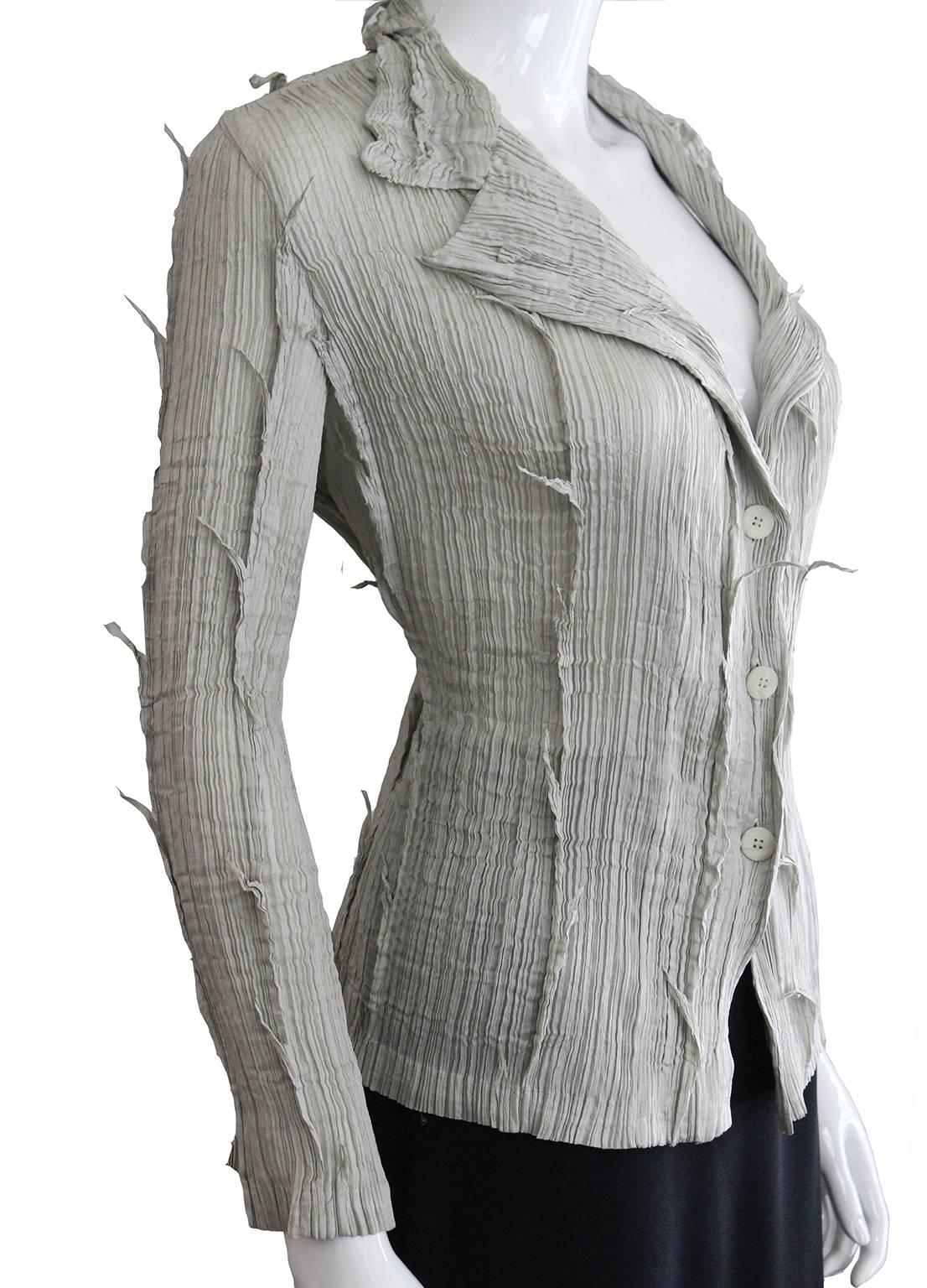 A rare and beautiful shirt/jacket from the Issey Miyake Fete line.This shirt/jacket is a wonderful dove grey colour,with pleats and grey attachments.It has a three button fastening, and a collar with lapels. 