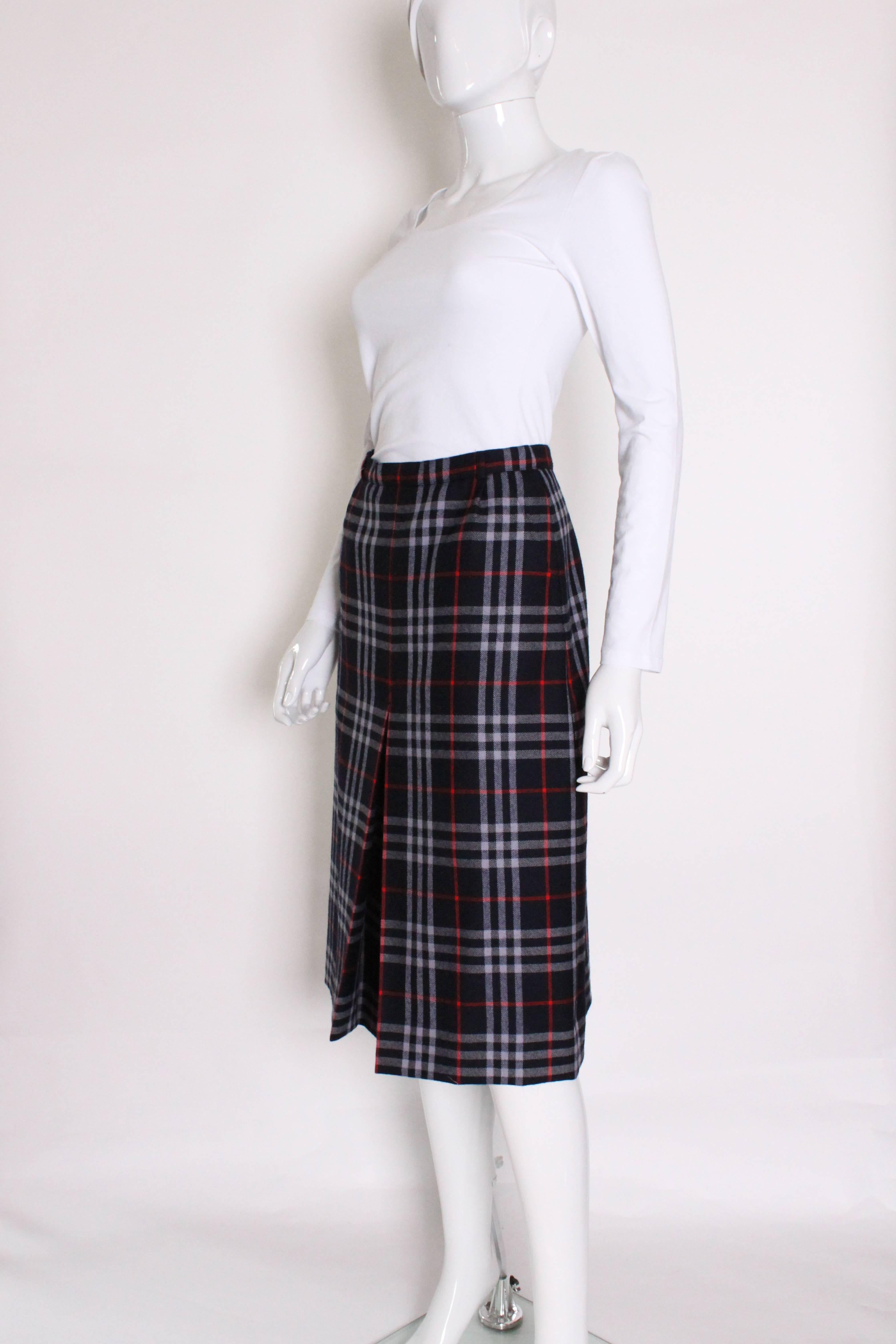An English classic, a check wool skirt from British fashion house Burberry.
This skirt has a navy background , with a red and pale blue check.
There is a central front pleat, 2 sloping pockets on the front and a central back zip. The skirt has