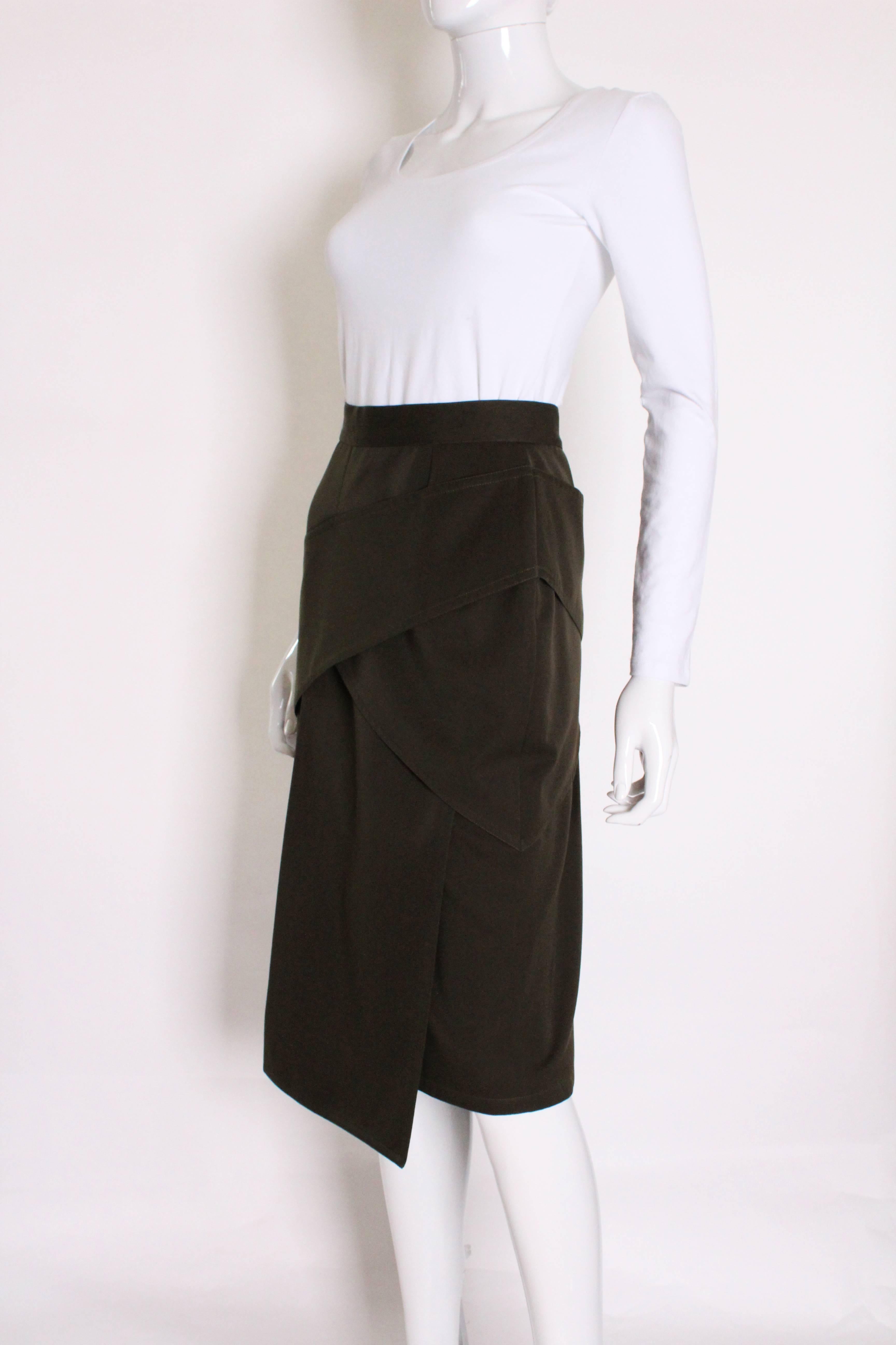 A great vintage skirt by Italian designer,Gianni Versace.
In a great sludge/khaki green colour,this skirt has a side zip,  and interesting draped layers on the front and back.
The skirt is 100 % wool, and Italian size 46.