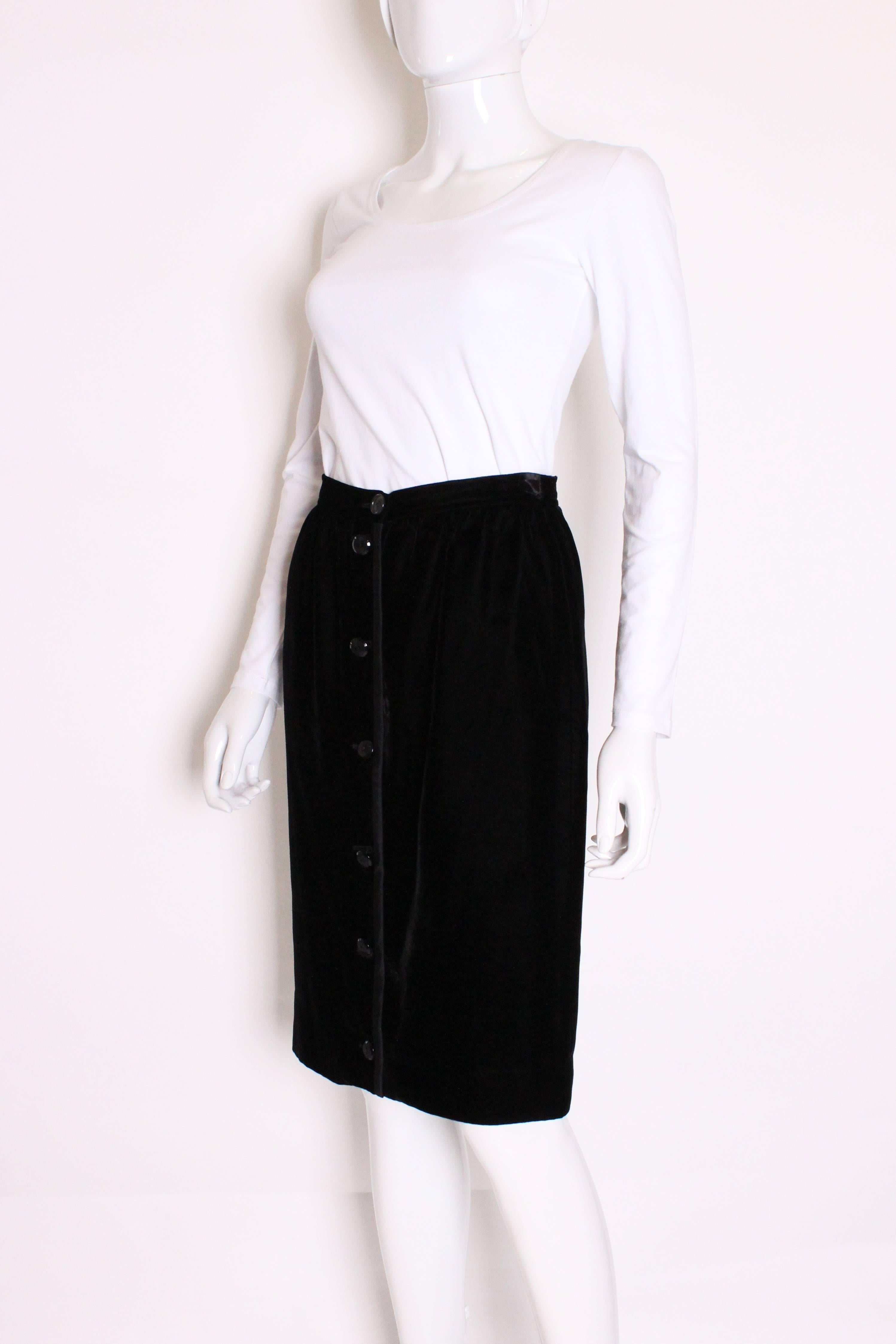 A super chic and super soft skirt by Italian design house Valentino. The skirt is
made of  black velvet, trimmed in silk, with a silk lining.. The skirt has a seven button opening.