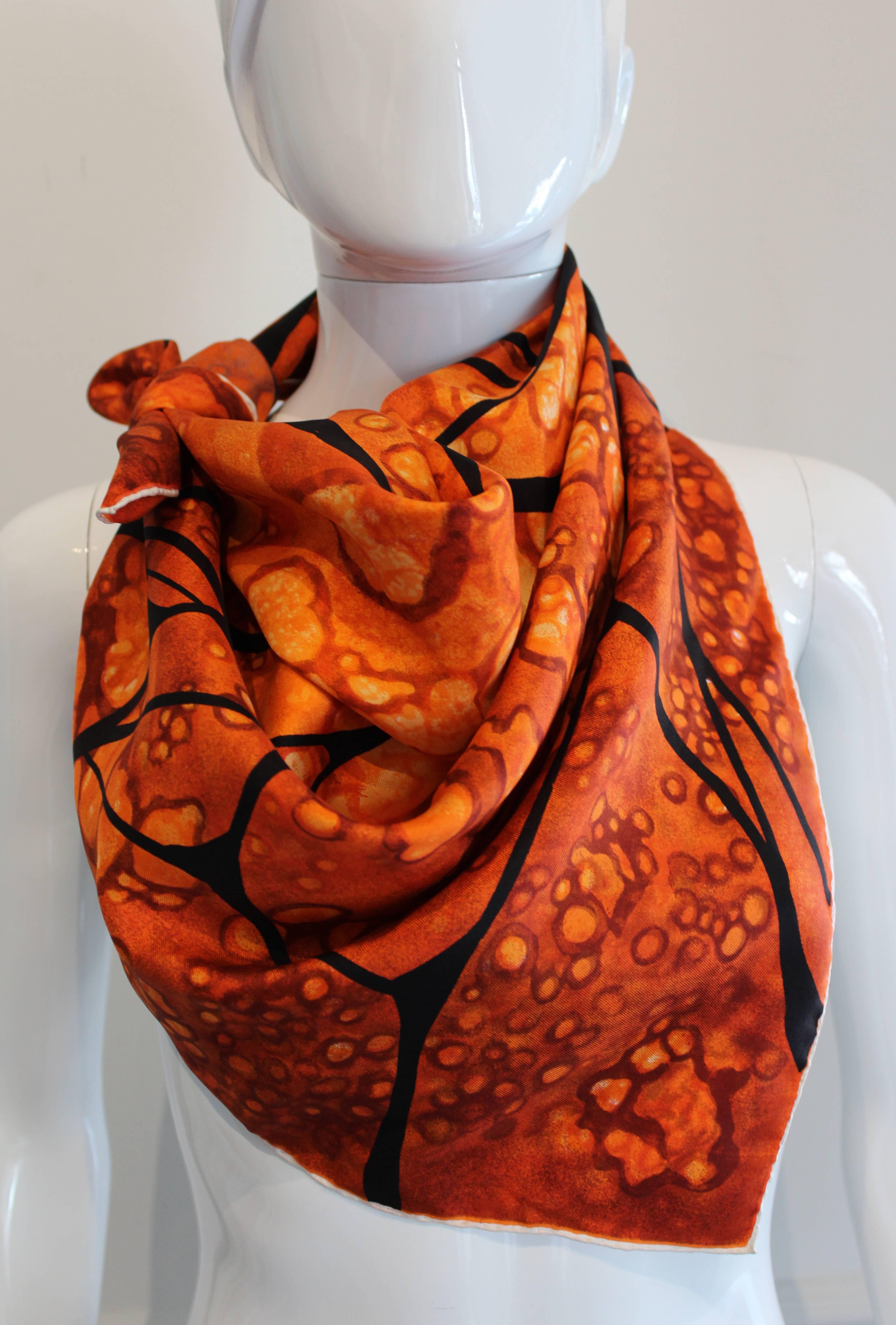 An elegant and usual silk scarf by French designer Jeanne Lanvin.This scarf has a thin white border with hand rolled edges. The body of the scarf is in various shades of orange, with a black abstract design. An interesting addition to any wardrobe. 