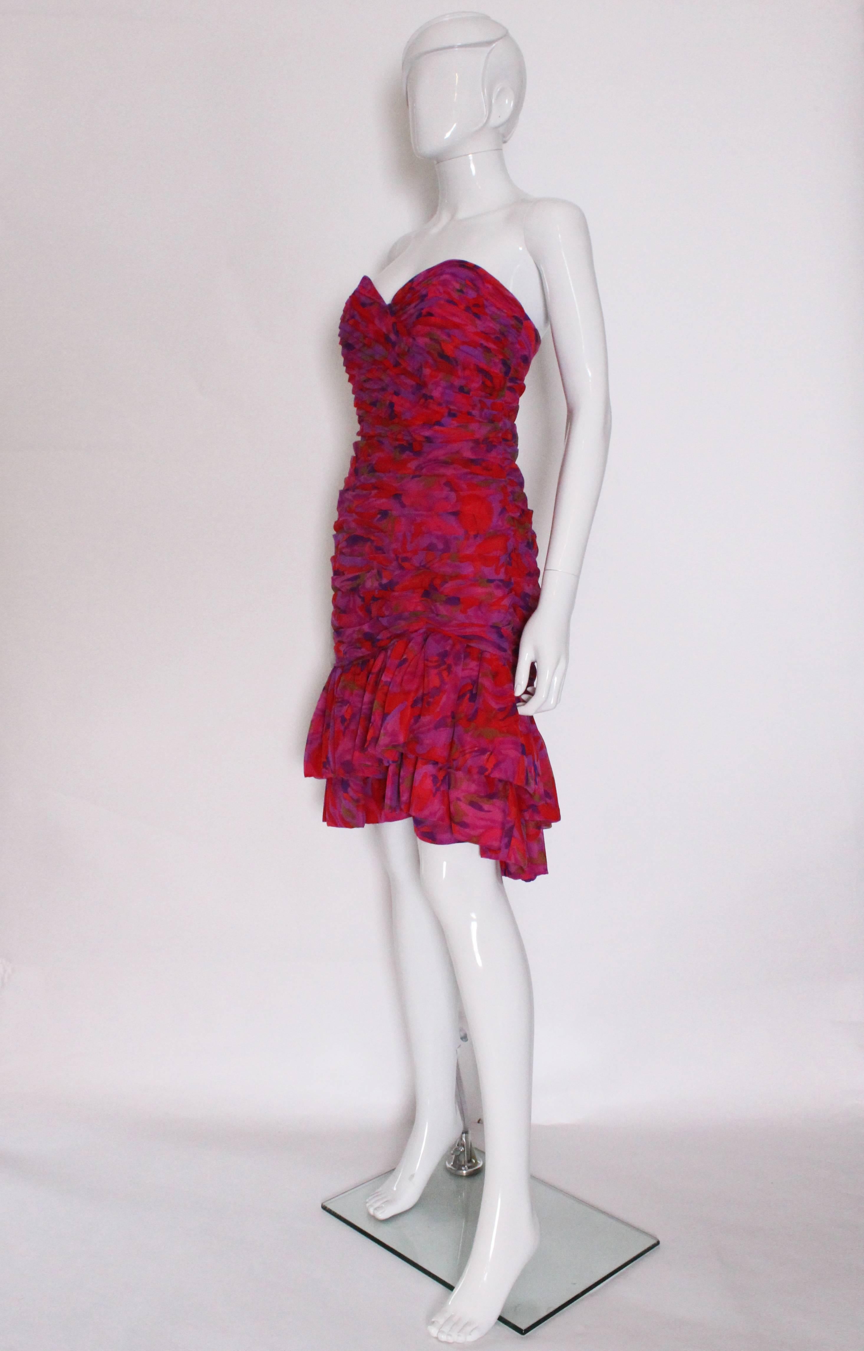 A wonderful party dress by British firm Quorum.
This dress is a wonderful mix of colours in red,purple ,mauve ,olive and pink.
The dress is strapless,with folds of fabric from the bust to a drop waist .The dress ends with two rows of frills