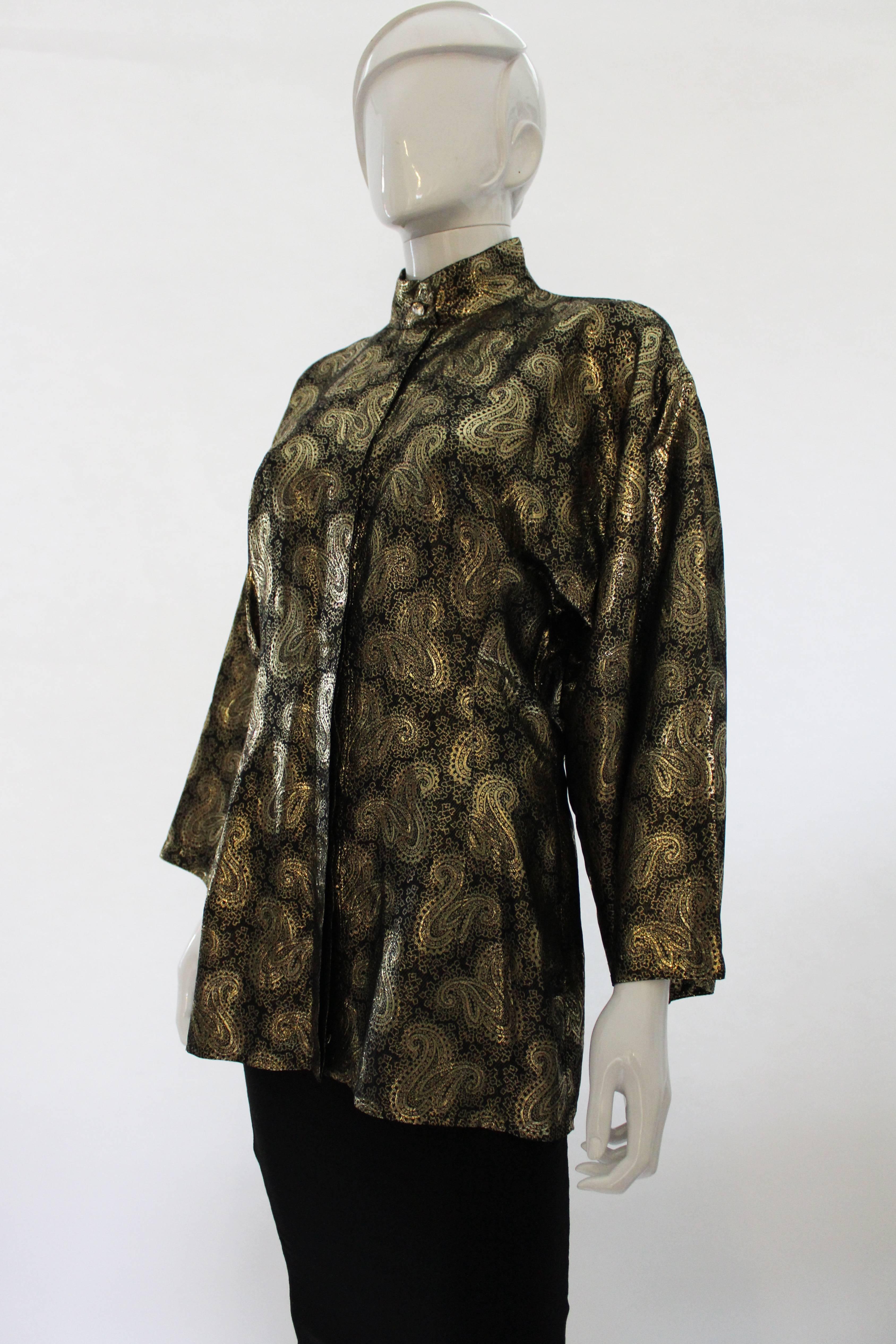 A glorious and glamorous evening jacket bythe late Gianni Versace. Made of a wonderful lame fabric, it has a black background, with a gold paisley design. The jacket/ shirt has a mandarin style collar ,one hidden row of buttons, and one decorative