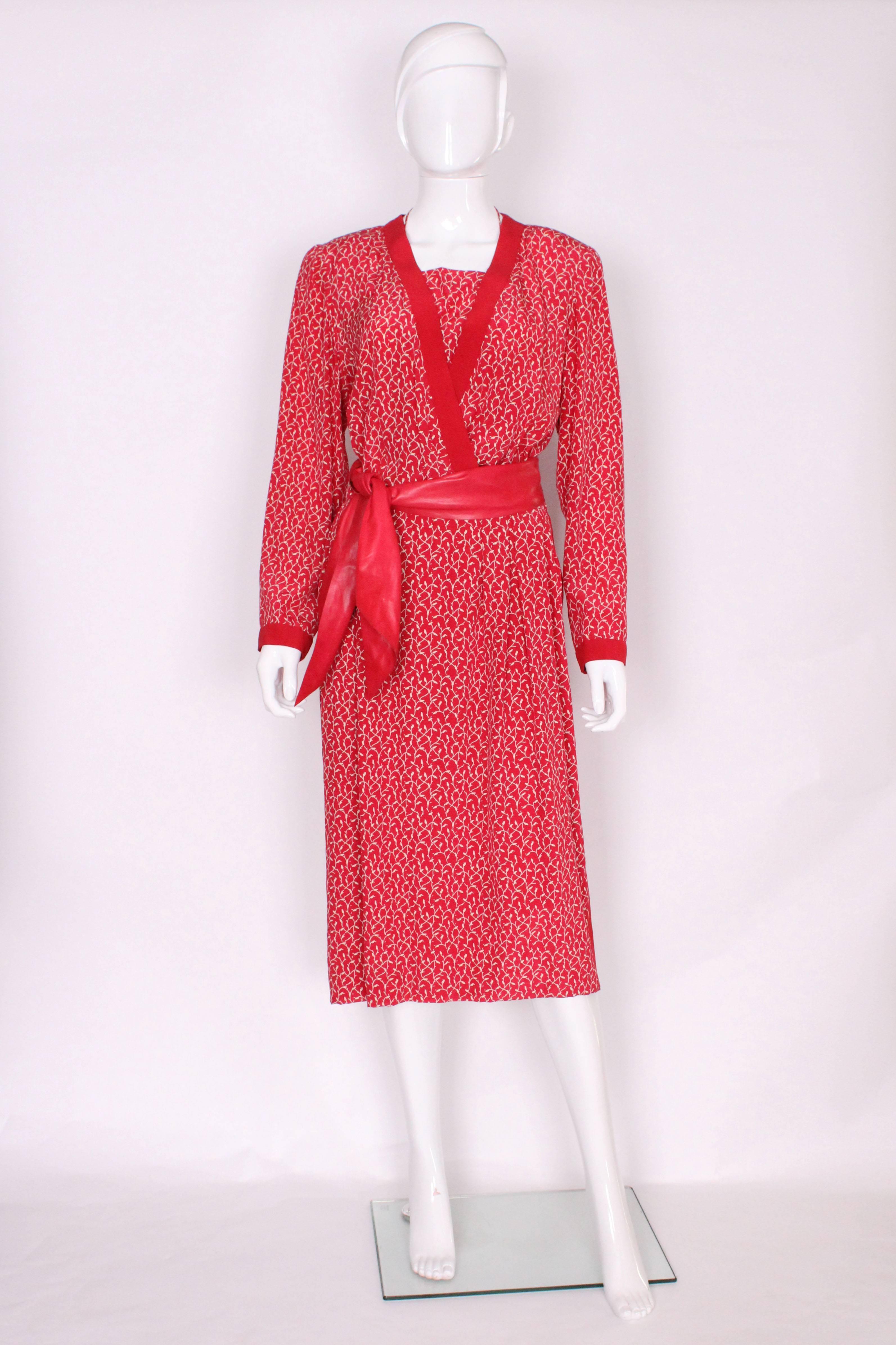 A wonderful couture dress by Christian Dior Paris, Spring /Summer 1979 , number 011774. In a red silk with a white leaf like design, the dress is edged in red silk at the neck , cuffs and side seams,,and has soft pleats at the waist and a pocket on