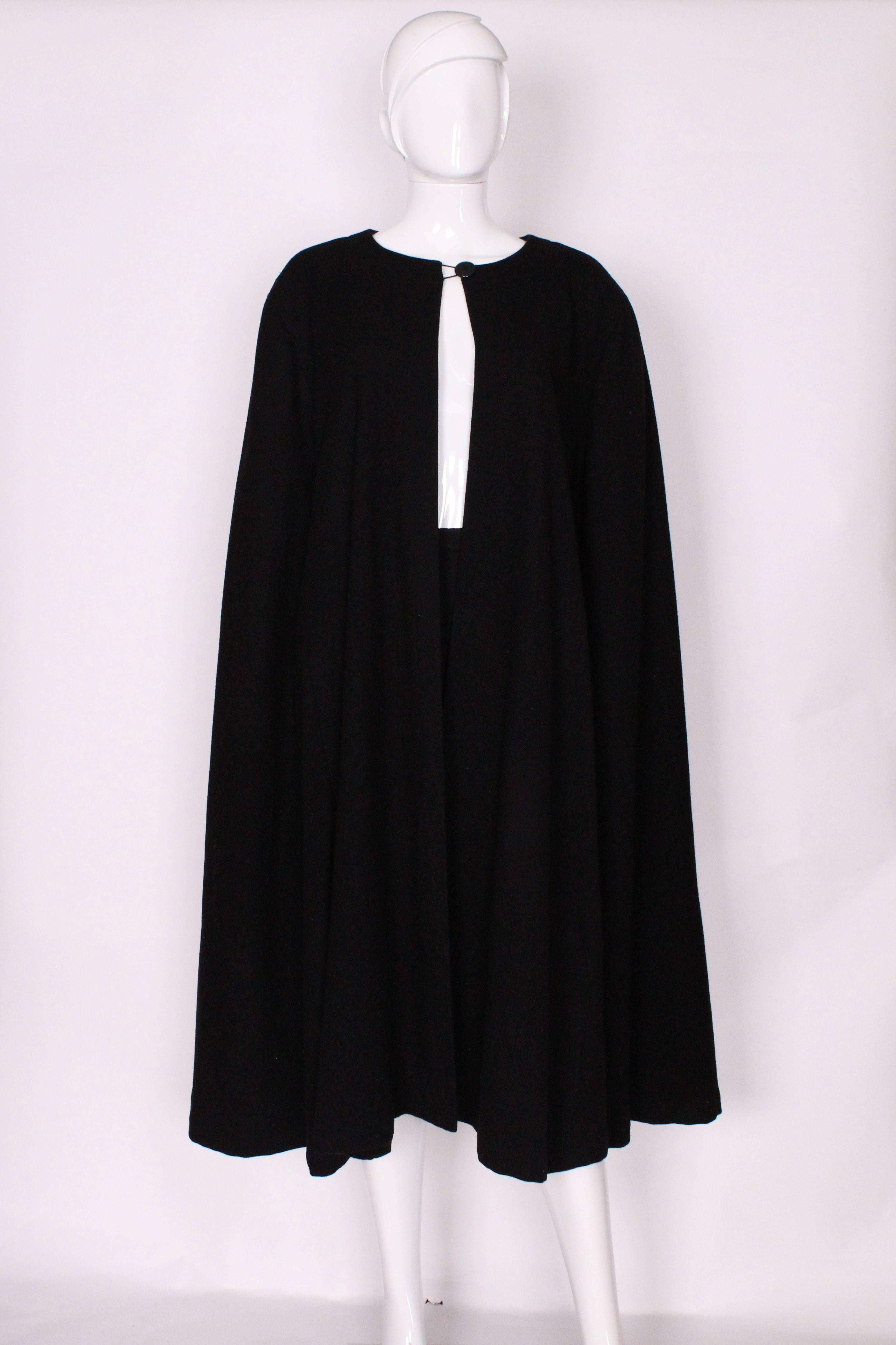 A stunning black wool cape by Yves Saint Laurent, Rive Gauche.The cape is collarless, with a single button fastening at the neck.