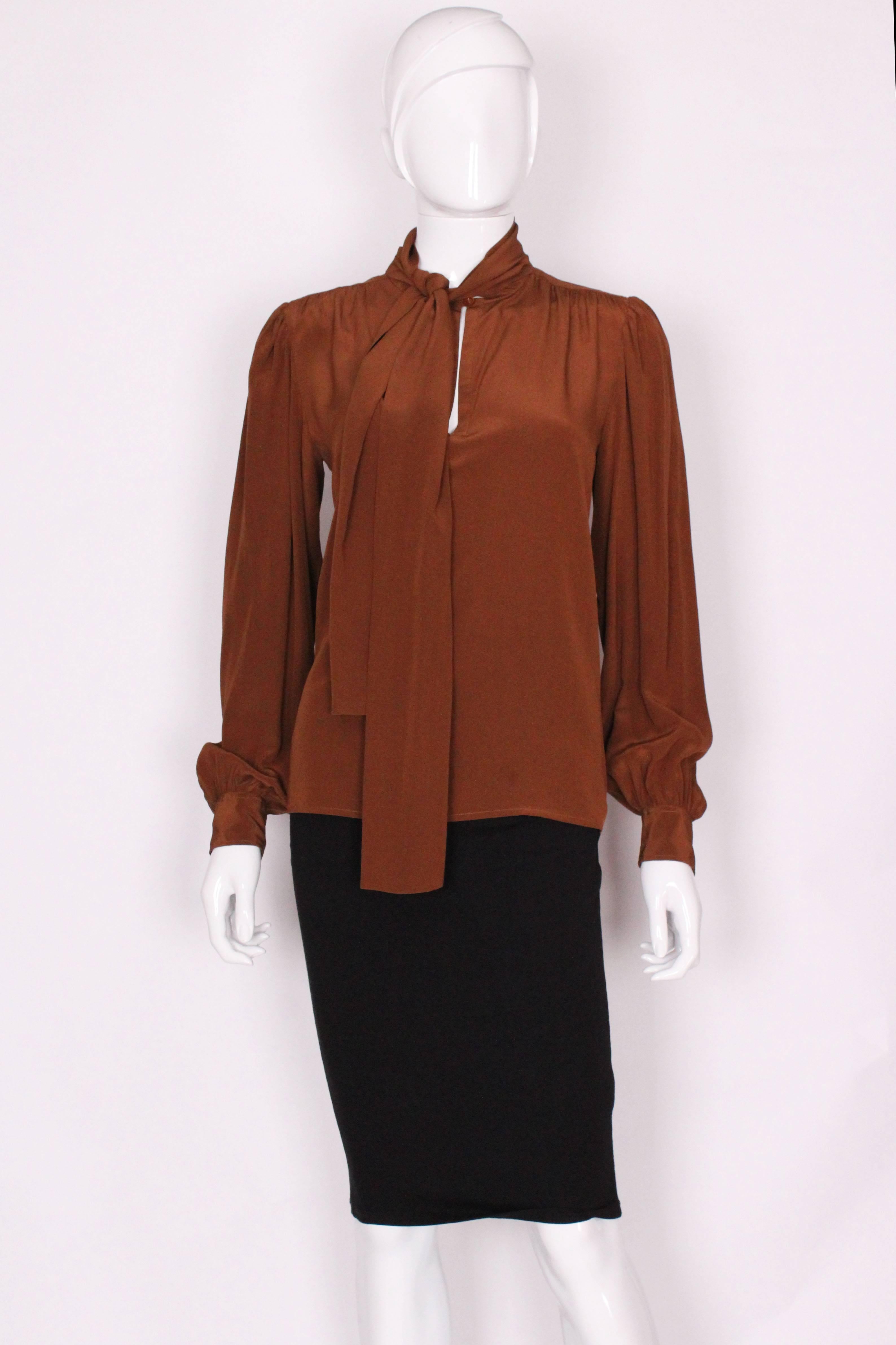 A great blouse for Fall, This silk blouse from Yves Saint Laurent  is a lovely chestnut brown colour. It has a one button opening at the neck, and one button on each cuff.There  is some gathering at the back and a pussy bow tie.