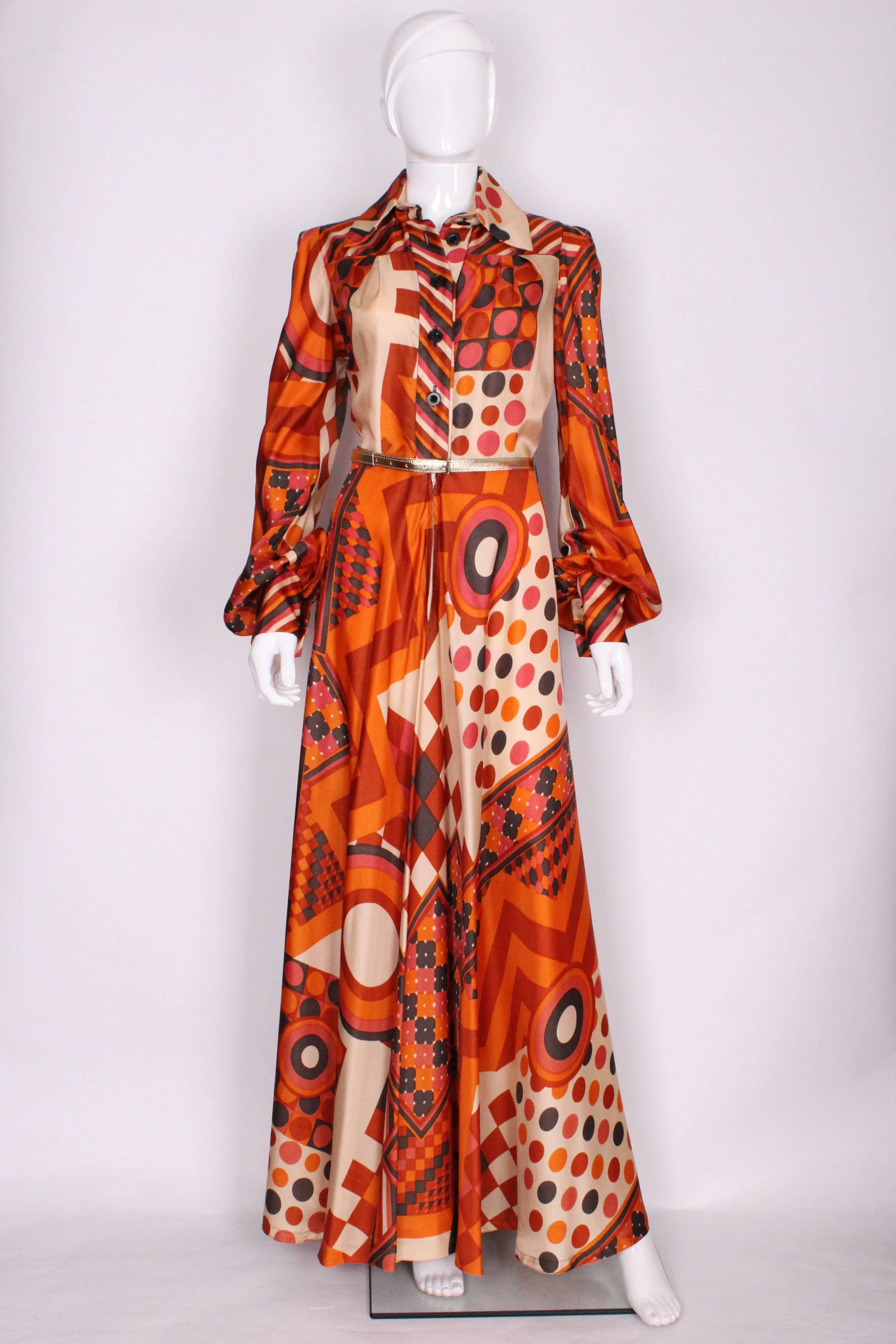 A wonderful gown for Fall by British designer Jean Varon ( John Bates).. In wonderful shades of pumpkin, burnt orange,black and ivory and a groovy and geometric print.This gown has a   large collar, 5 button opening down to the waist and a zip from
