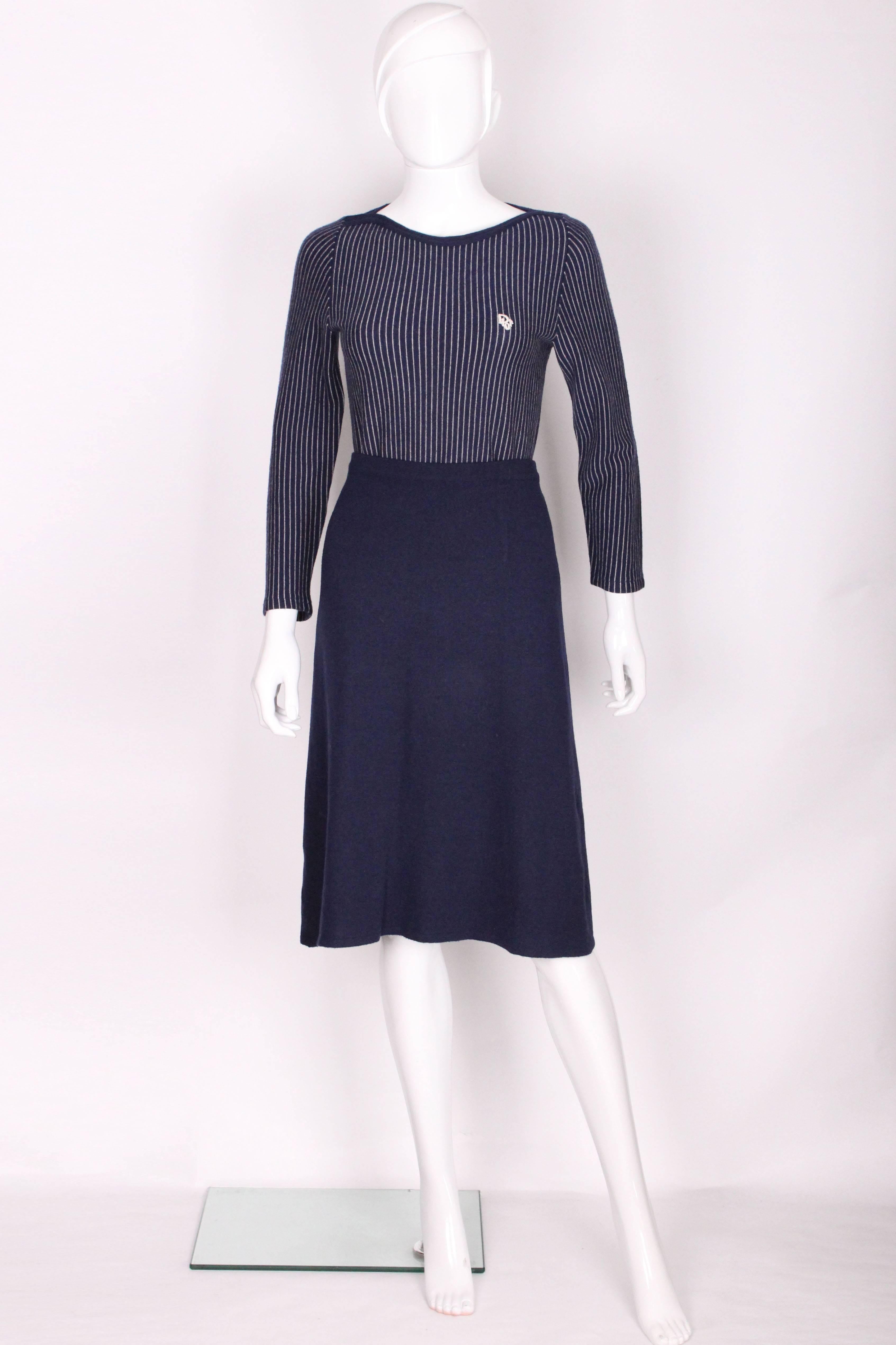 A perfect outfit for the chilly days to come. The 2 piece by Christian Dior London, has a blue and white stripe top ( vertical stripes), with a slash neckline with a blue trim and white Dior logo on the front. The skirt is a navy blue colour and is
