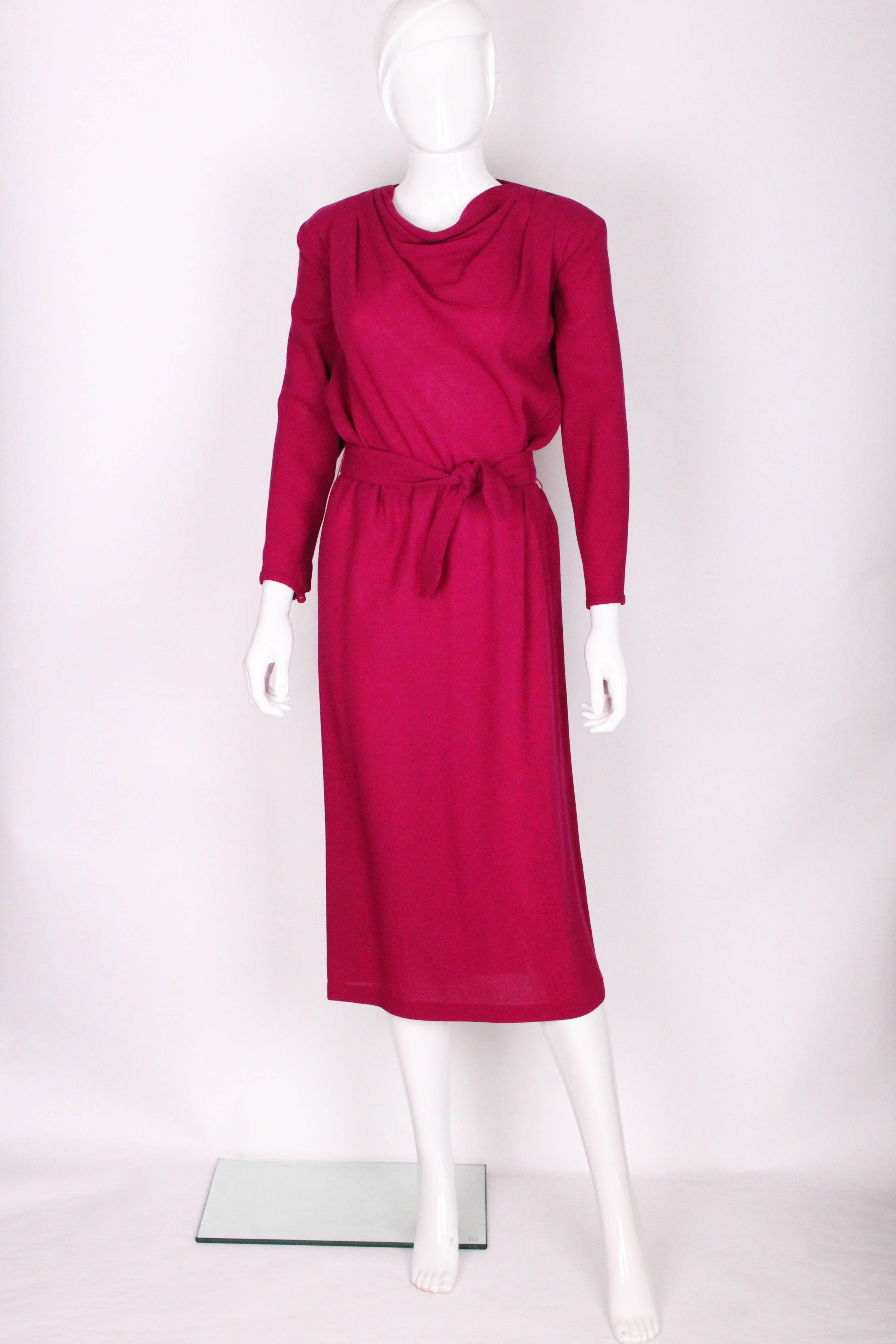 A great dress by British design house Biba. In an eye catching shade of purple/pink and in an easy to wear wool crepe - this dress can take you from work to play. It has a slight cowl neck with pleating on each shoulder, elbow length sleeves with a
