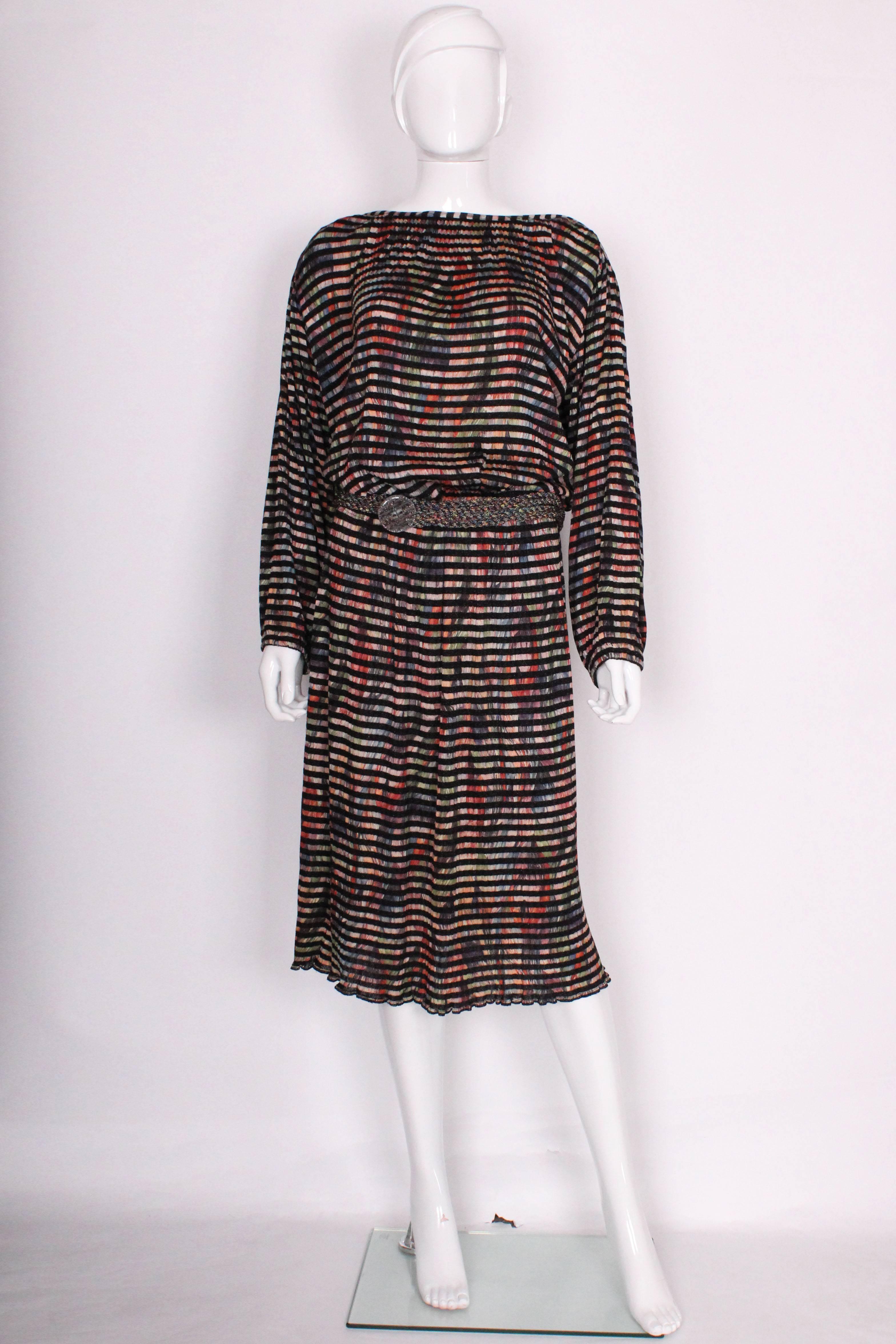 A great easy to wear dress from Missoni,main line.This dress has black horizontal stripes over a multi colour background. It has an elasticated waist and elastic at the wrists.It has a matching woven belt.
