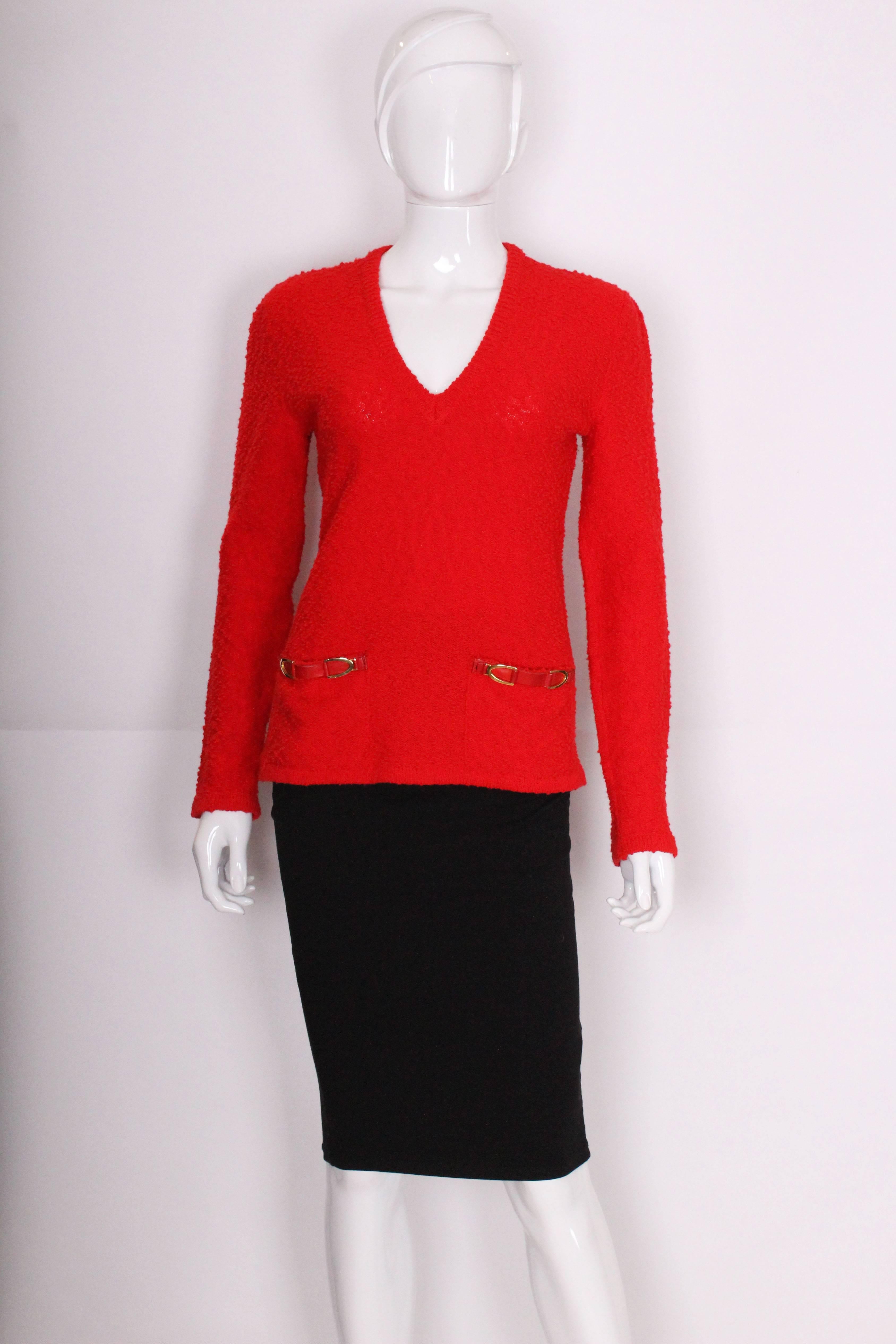 A great jumper for the festive season by Celine , Paris. In a red boucle wool with two pockets with stamped hardwear detail.The jumper is v neckline with ribbing around the neckline,hem and cuffs.