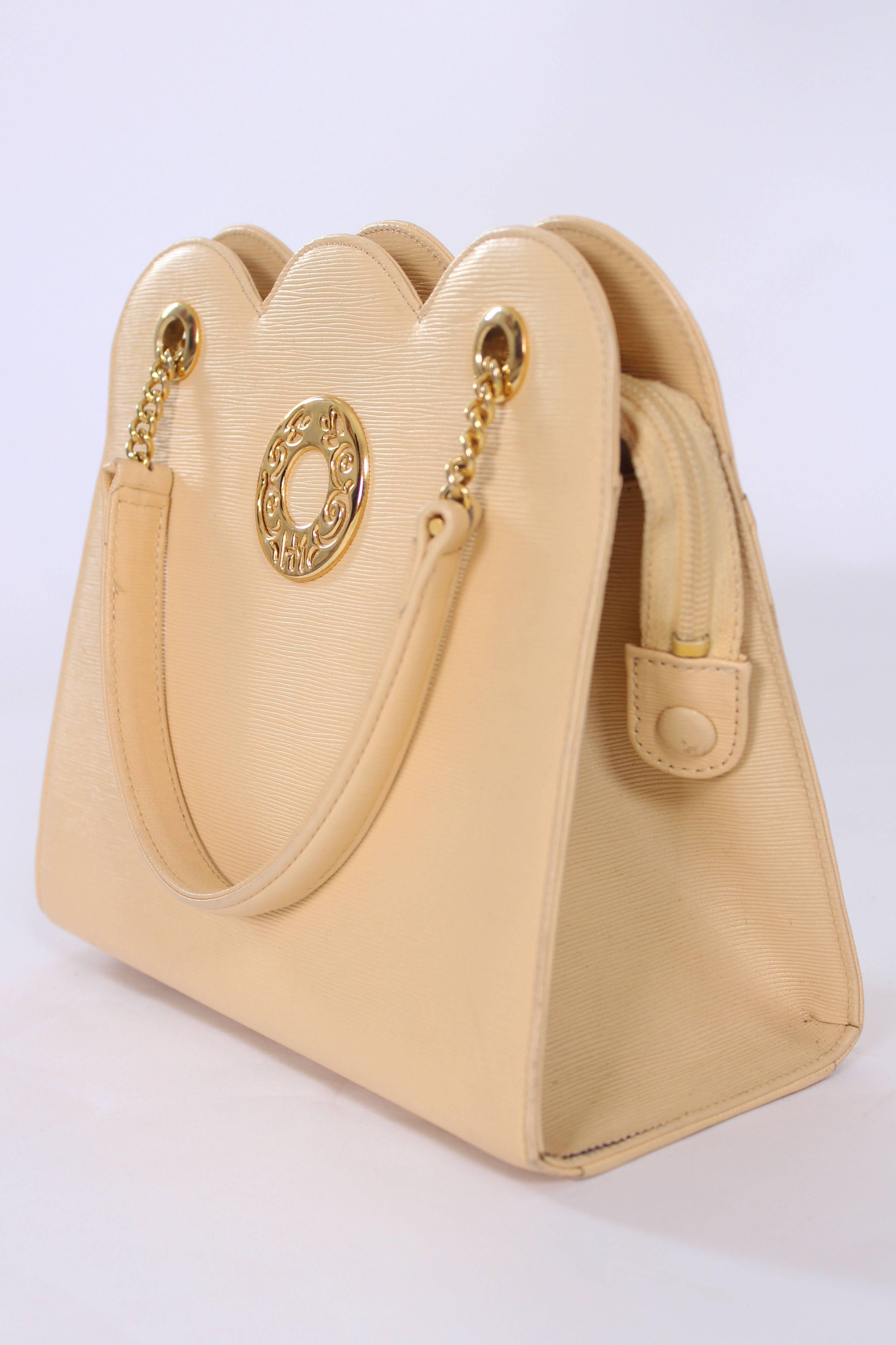 A chic pale yellow handbag in ribbed leather with scalloped edging, by Japanease designer Hanae Mori. This bag has two leather handles with chain ends, and a zip top fastening. There is a pouch pocket and zip pocket inside and a slip pocket on the