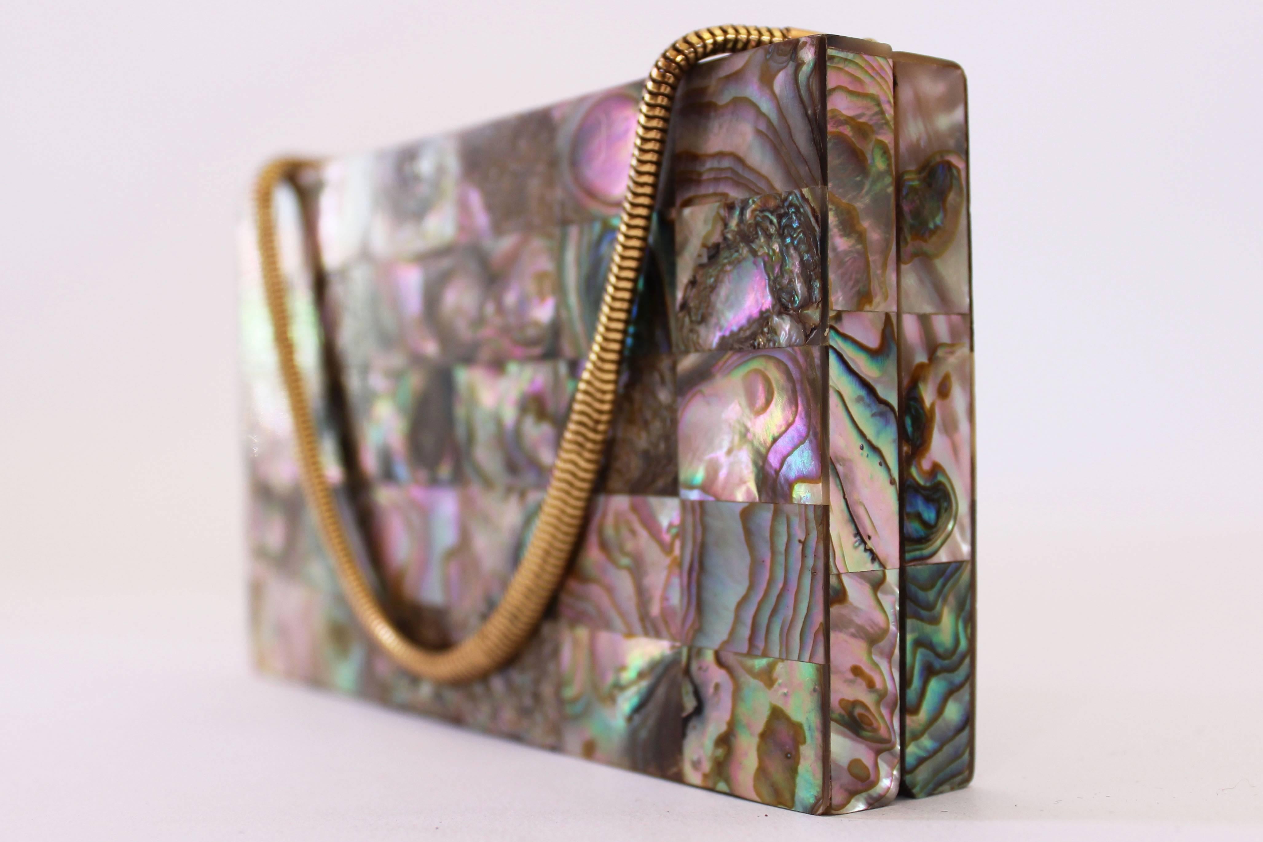 A chic 1940s minaudière in excellent condition by Evans. This one is covered in small, iridescent abalone shell tiles. The interior is coloured gold and is also in excellent condition though sadly missing the original contents. The bag has a gold