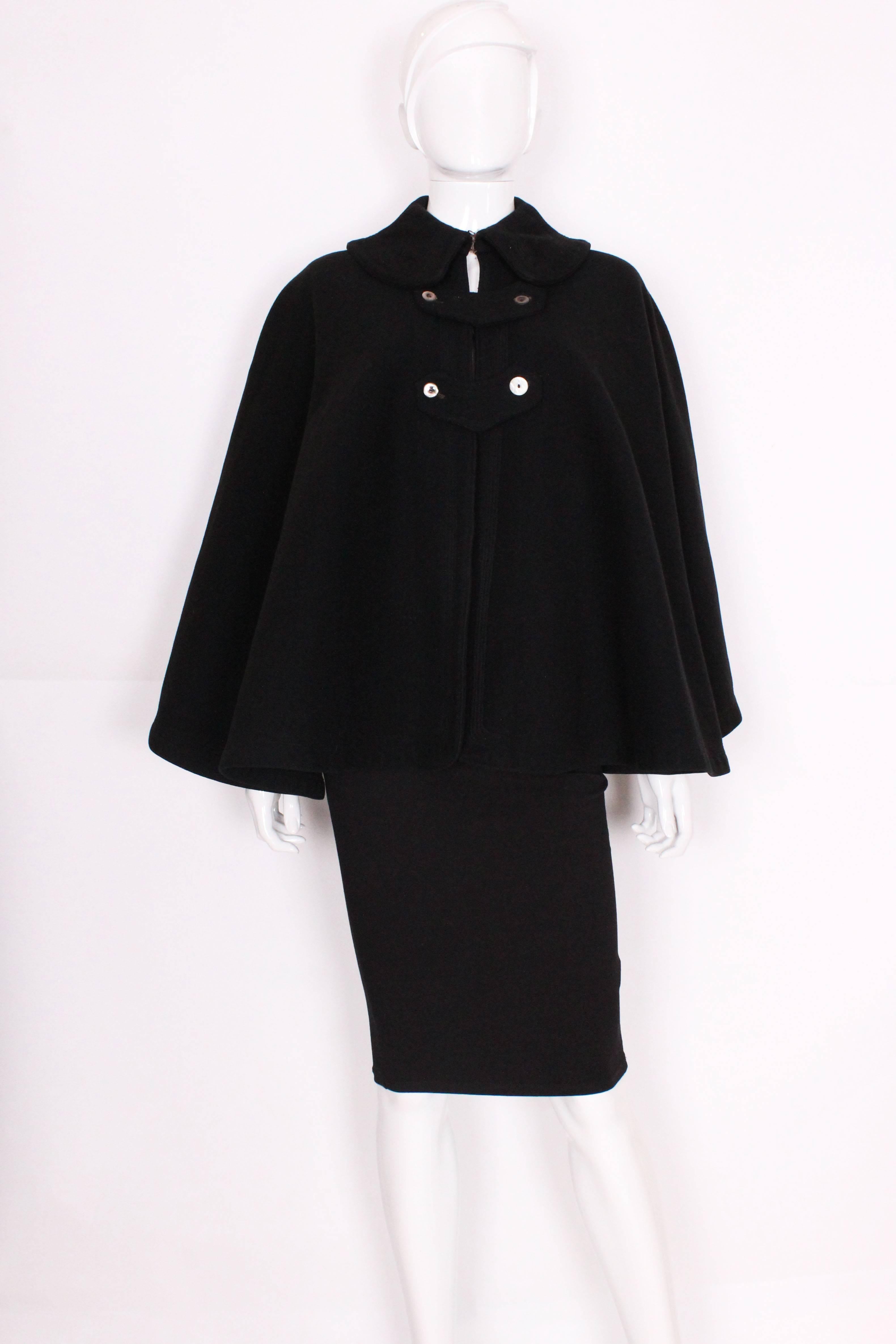 A heavy wool cape in a dark navy blue, useful and stylish for layering over outfits for the party season.This cape has a deep collar  (4''), with a hook and eye fastening.It has two rows of button attached strips to fasten the cape , thought these