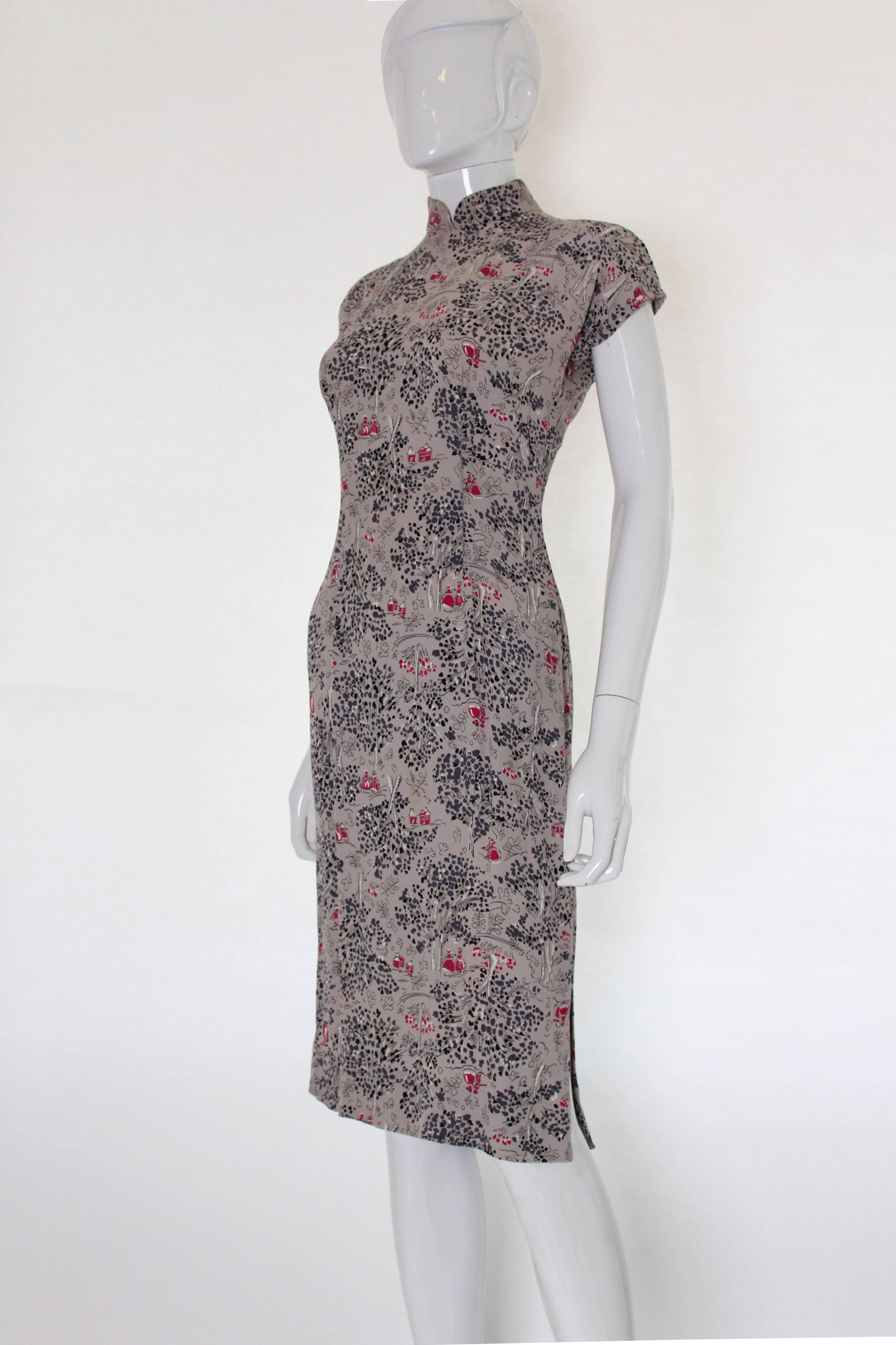 This is a great dress in a wonderful detailed print. The dress is rather Chinese inspired, with a stand up Mandarin collar, cap sleaves and close fit Cheongsams syle look. The background colour is light mushroom grey with the print in deep pink,