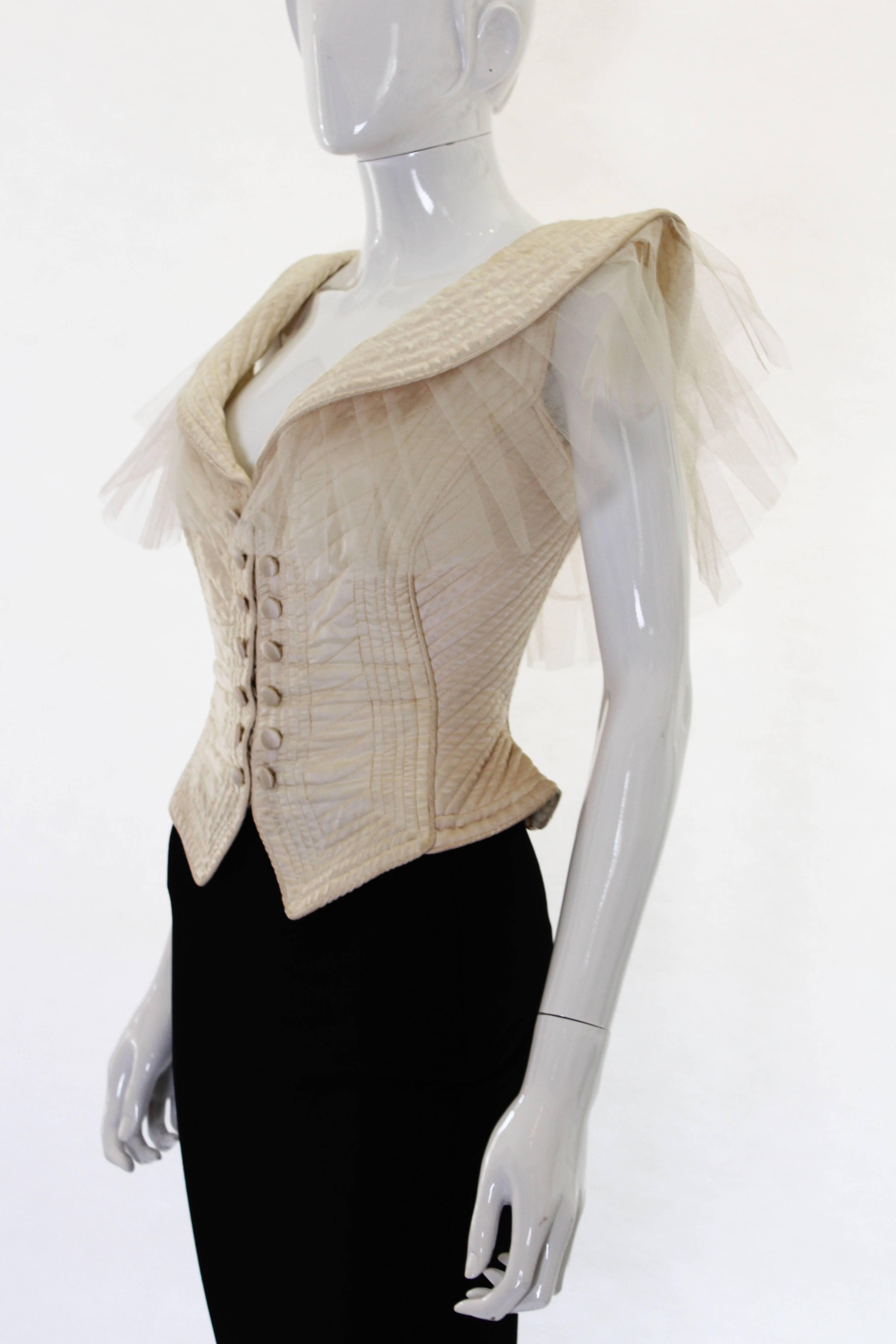 A stunning 1970s ivory satin waistcoat by Penny Green. It has a padded detail and stitchwork that is shaped so that it accentuates the waist. The sleeves are made of netting that comes out from under the collar in an almost wing like way. This item