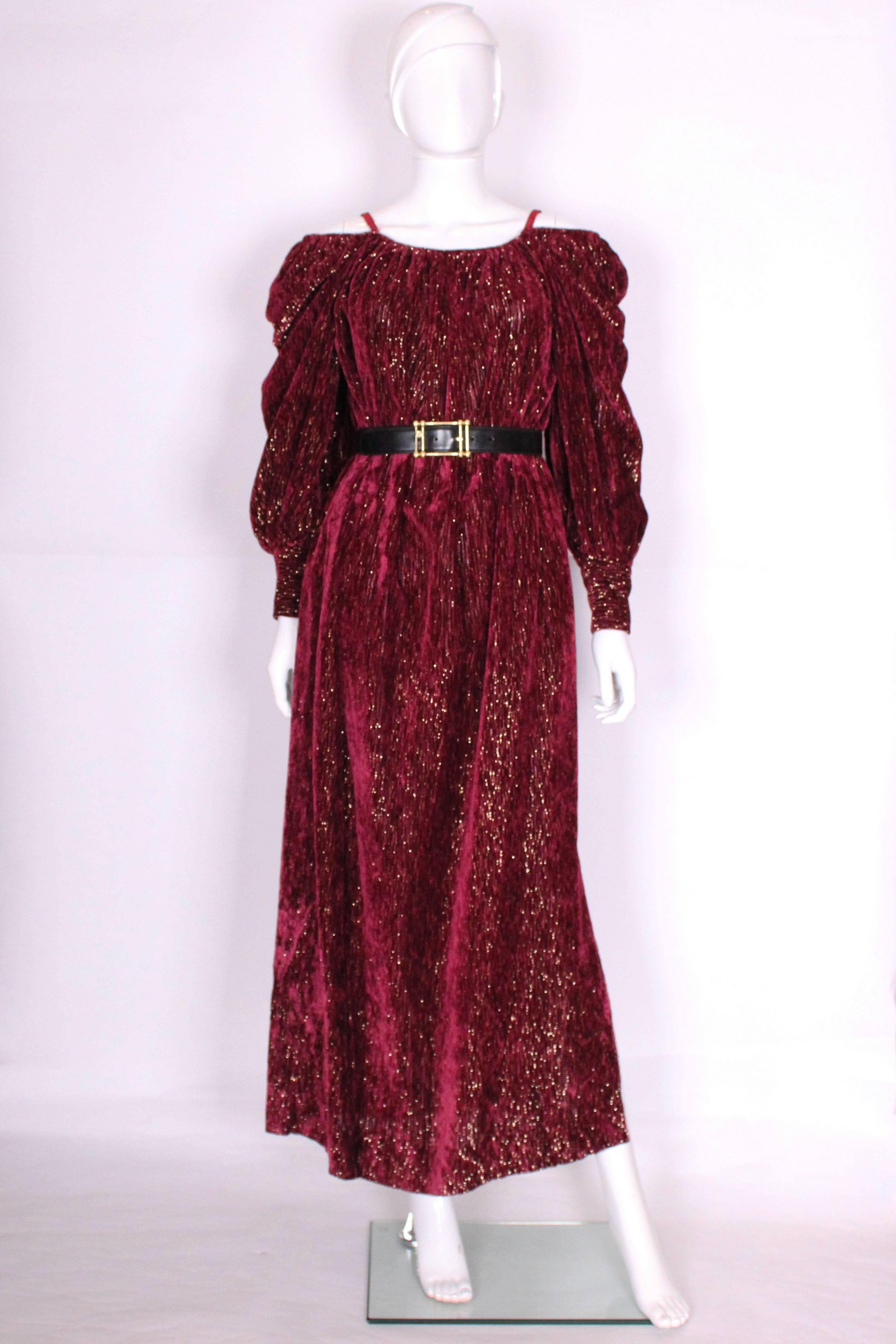 
A glamorous gown by Christian Dior Boutique, Paris. In a wonderful burgundy and gold ribbed fabric , this gown can be worn on or off the shoulder. There is a 17'' slit on the left hand side, 2 pockets at hip level, and a wide 3 button cuff.

