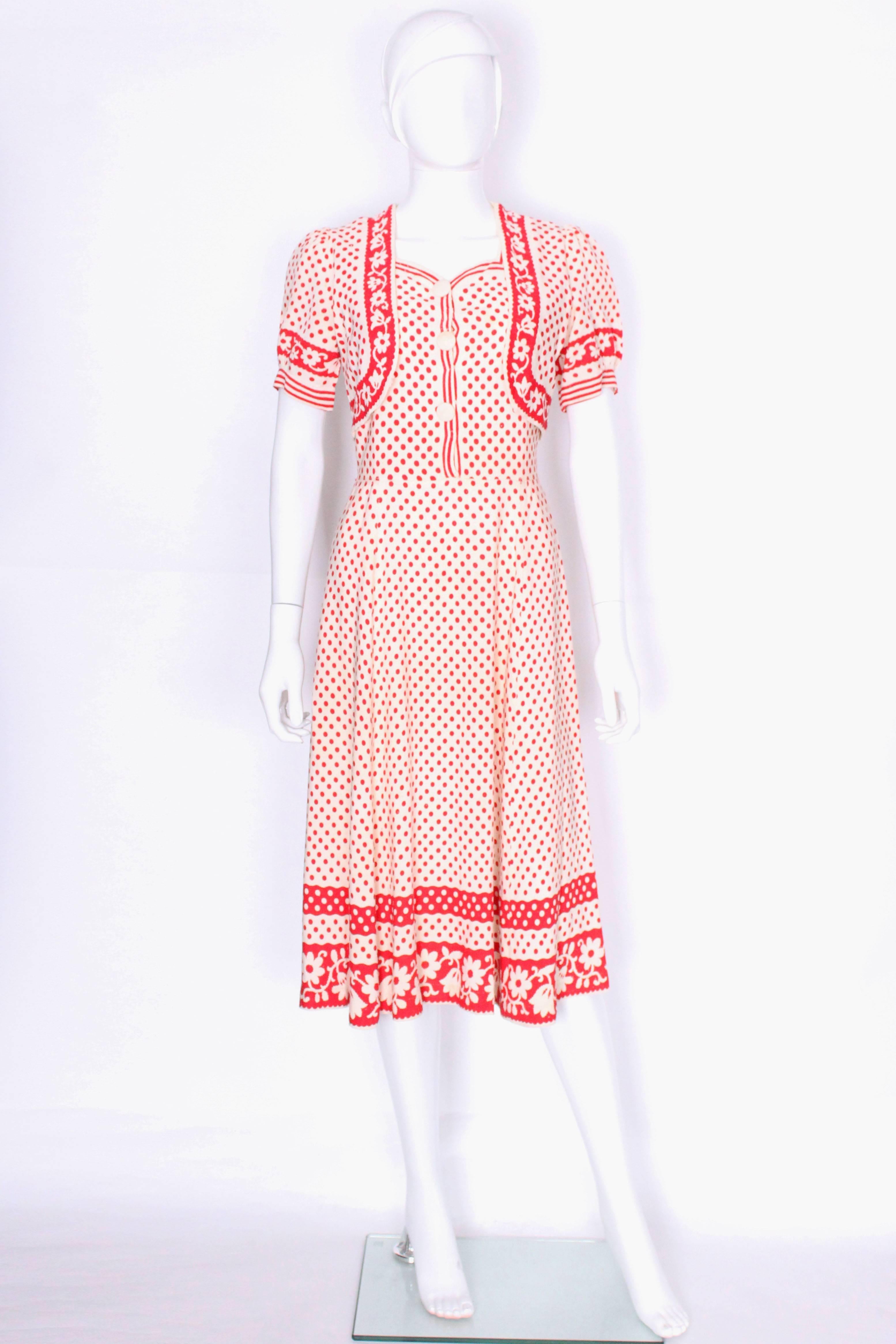 A charming and chic French dress dating from the 1940s. The dress has a sweetheart neckline and 3 buttons down the front that undo underneath with a popper. There is a short puff sleeved bolero that sits over the the top but is actually attached on