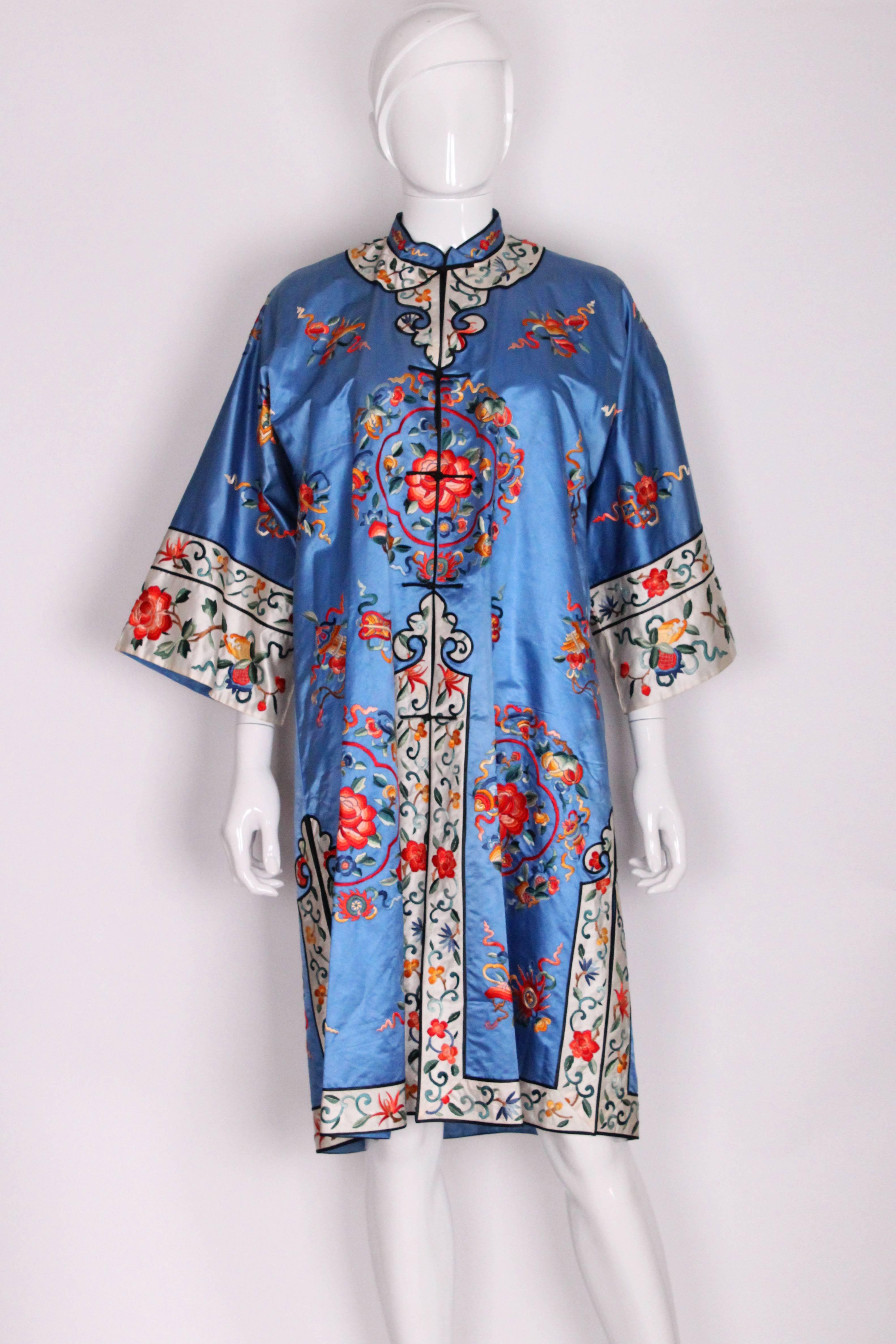 A great silk jacket from China, in a wonderful blue and covered in brightly coloured embroidery. The body of the coat is a wonderful China blue with floral embroidery and it has a white border on the cuff, hem and yolk, with embroidery along it. The