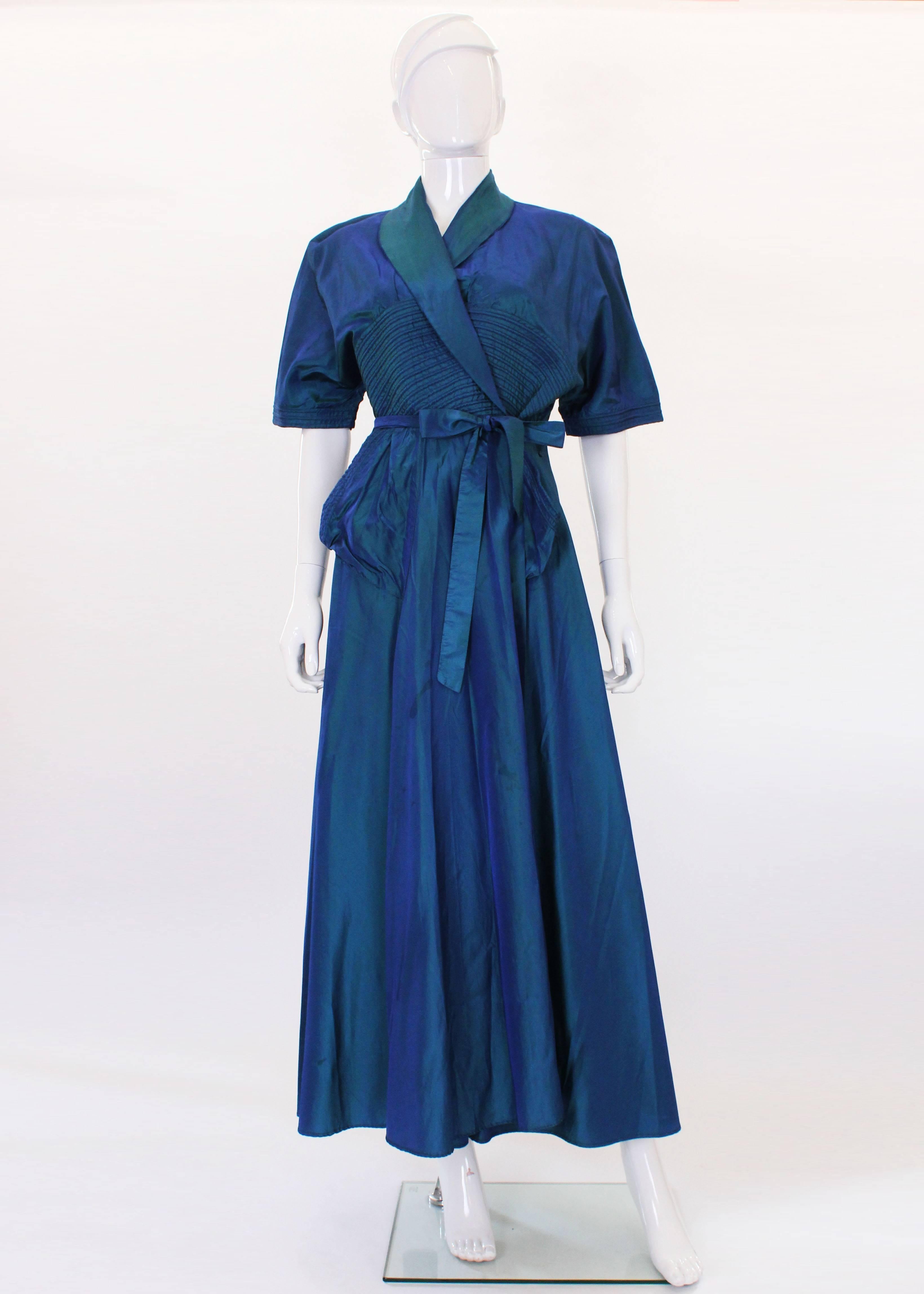 A stunning gown or very glamorous house coat from the 1940s. In a wonderful blue, this gown is a real head turner. It has short leaves with ribbed stitching detail on the sleeves, bust and pockets. It is a wrap over dress with a belt in the same