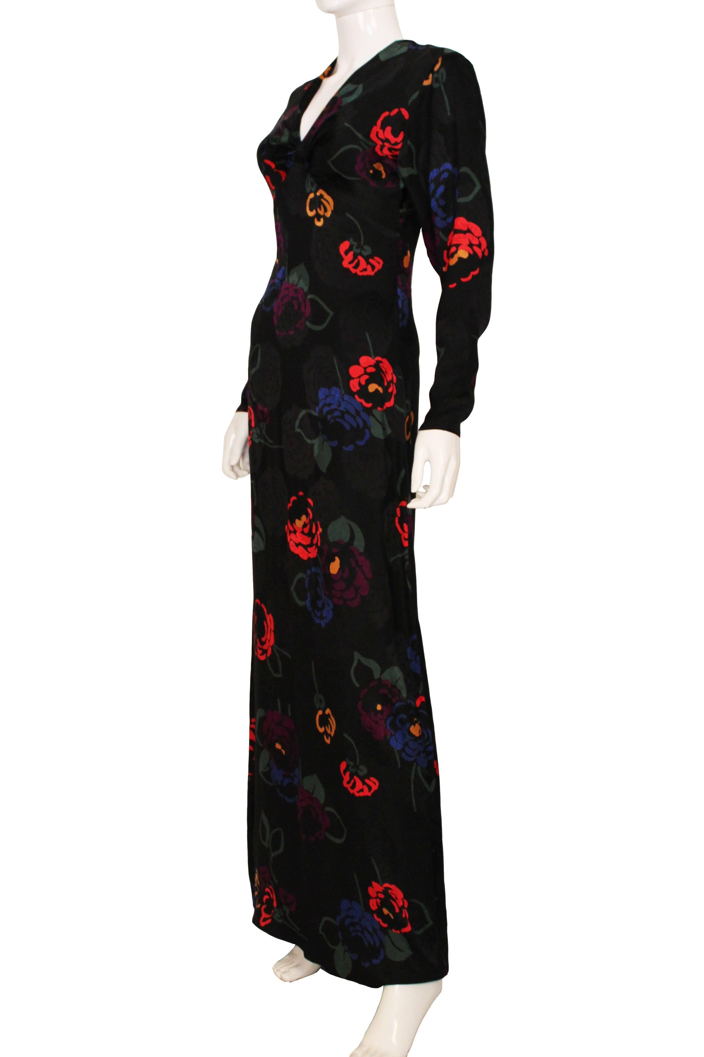 This is a stunning 1970s evening dress made from a glossy silk fabric. The main colour of the dress is black with red, yellow, purple and blue rose prints, with green leaves. The print is quite a modern floral print as it is a block colour design