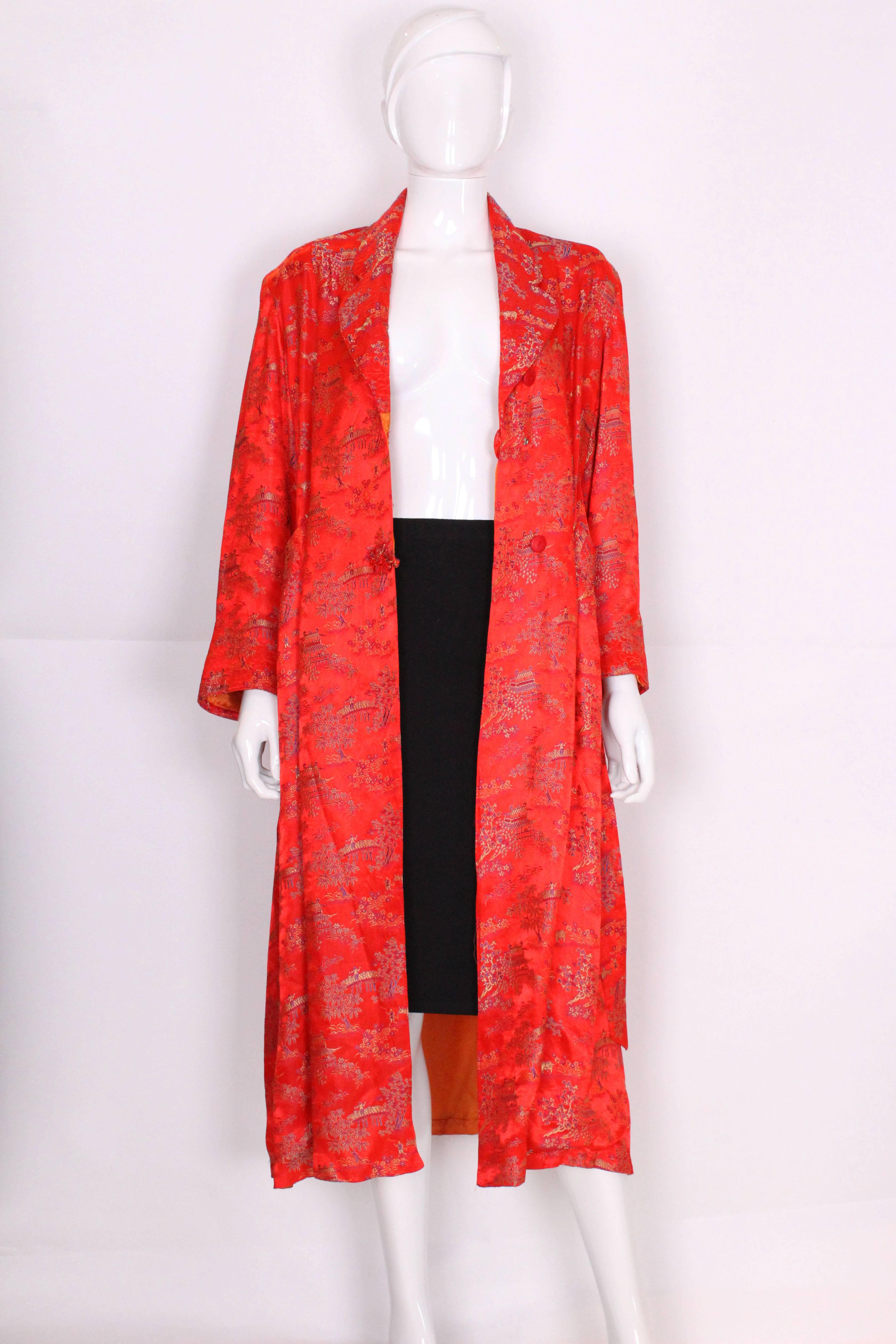 This dressing gown by Cherry is in a wonderful red with Chinese detail with an orange lining. The collar is cut away with quilted detail, that is also found on the cuffs and pockets. The gown has shoulder pads, a self tie belt and an internal tie