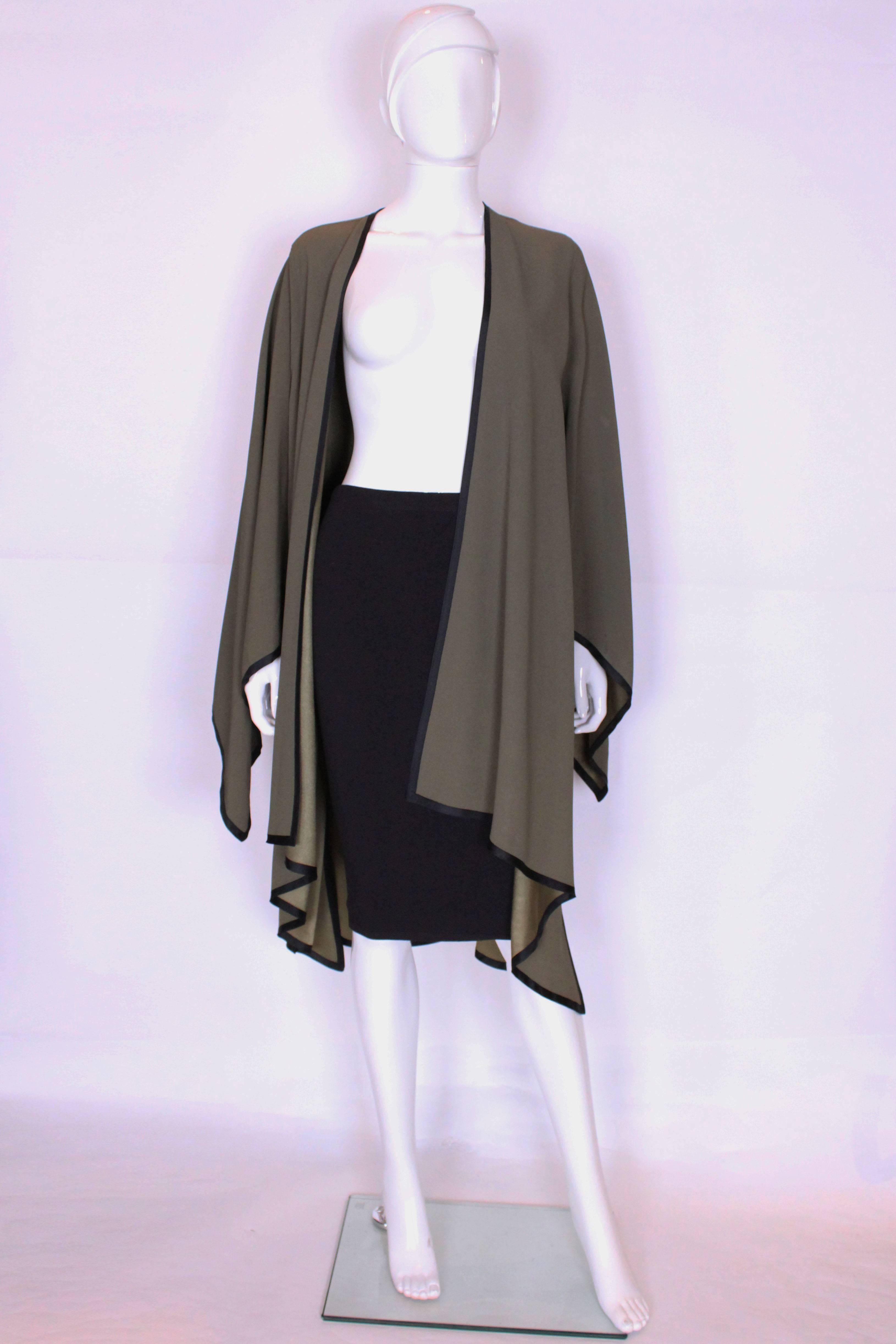 A great green over jacket by Yves Saint Laurent Rive Gauche.
In a soft sage green and trimmed in black this jacket works well with trousers or a skirt/dress.It has a wonderful drape,  the hemline style is the same for the  sleeves and hem.