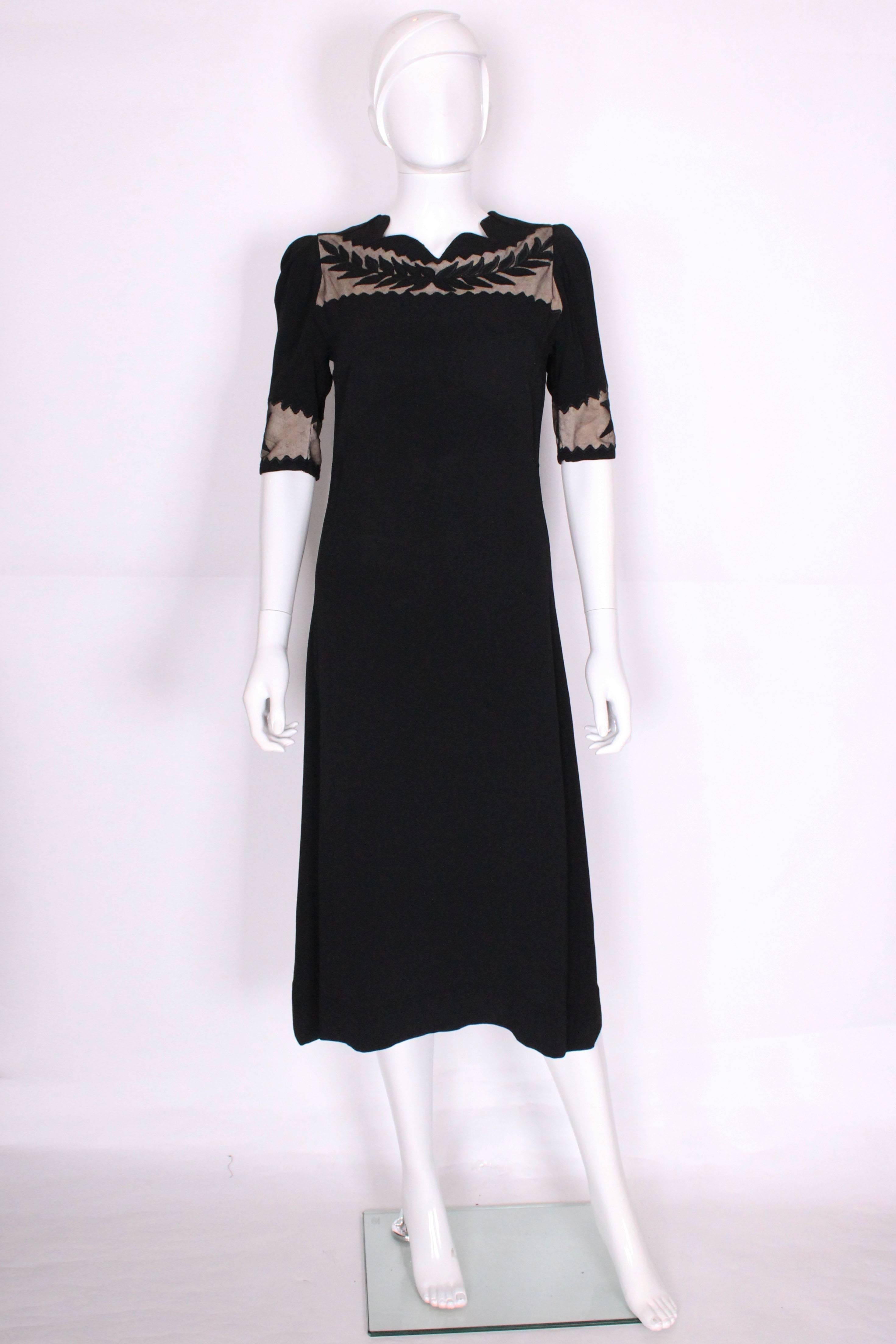 This is a charming and chic dress from the 1940's with some great detailing. It's made of a black crepe with nude coloured fabric in the cutout sections. There are black leaf applique details on top of the nude cutouts on the sleeves and bust. The