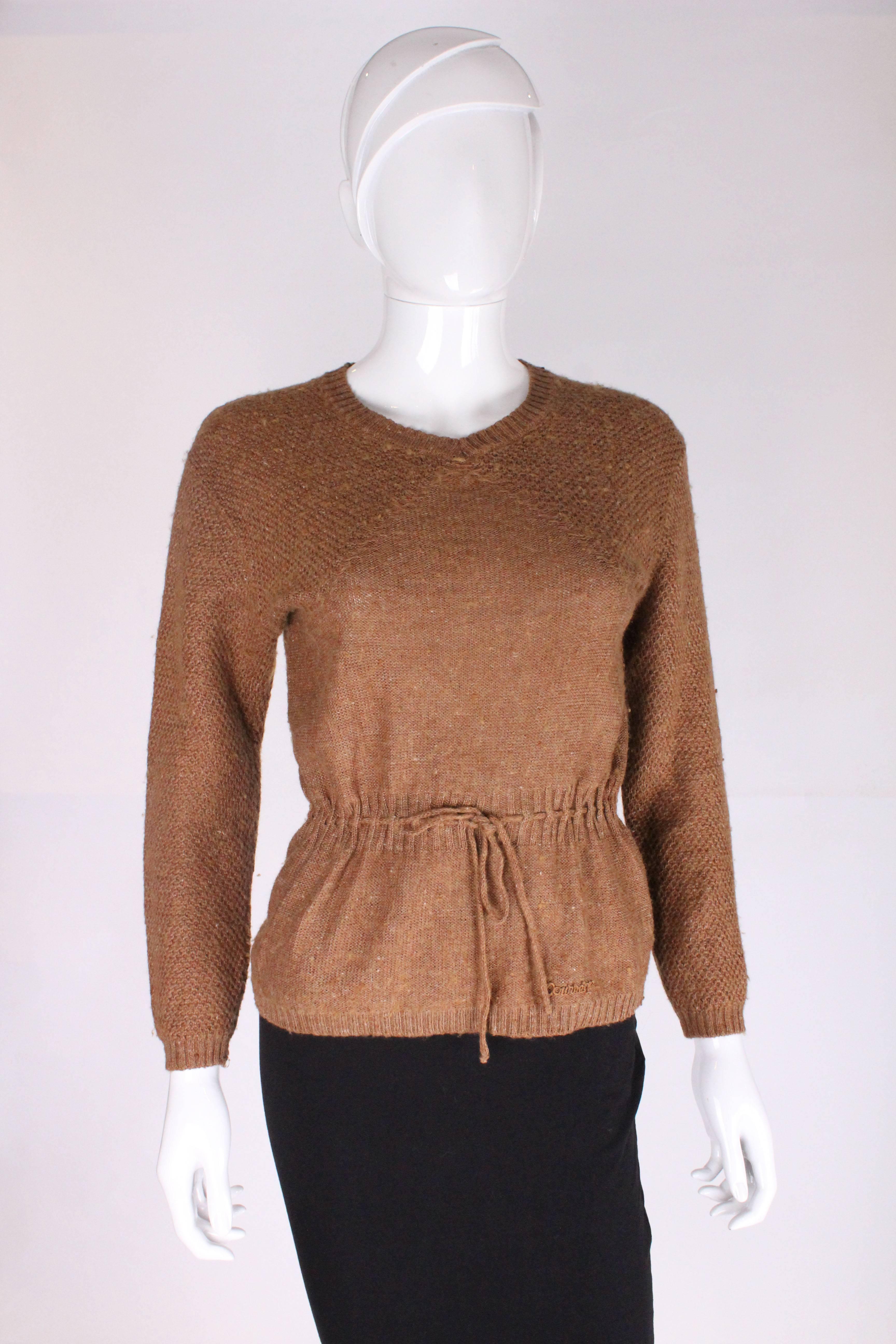 A great jumper by French designer Andre Courreges. In a tobacco brown wool  mix,this jumper has a v neckline, and drawstring waist.There is honeycomb stitch detail on the sleeve and yoke, and Courreges applique on the lower left side.