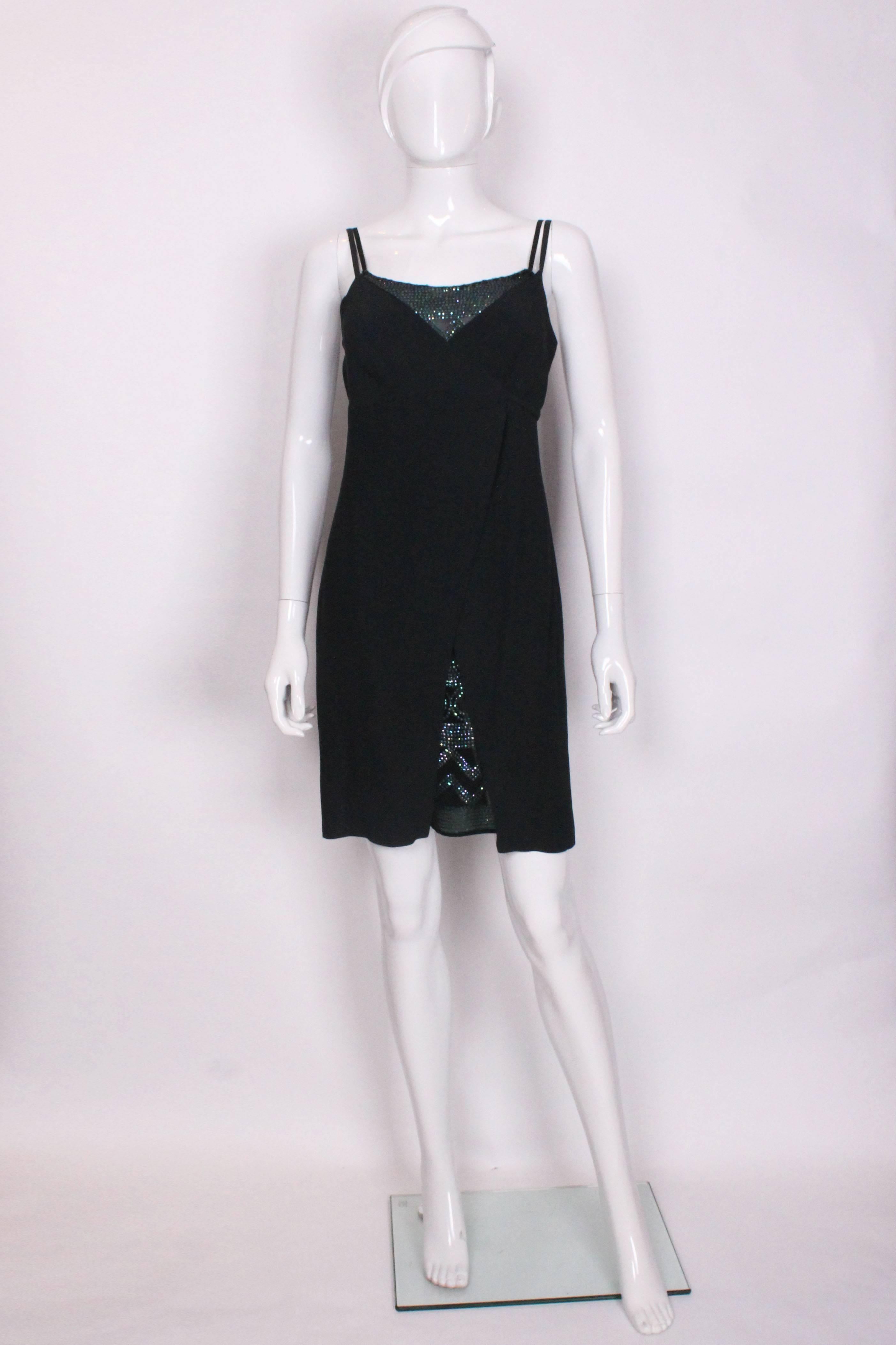 A chic cocktail dress by La Perla. The inner dress is embellished with sequins in purple, green and blue in a geometric print .The outer dress is dark green , which wraps around and ties under the bust. There is an invisible side zip.