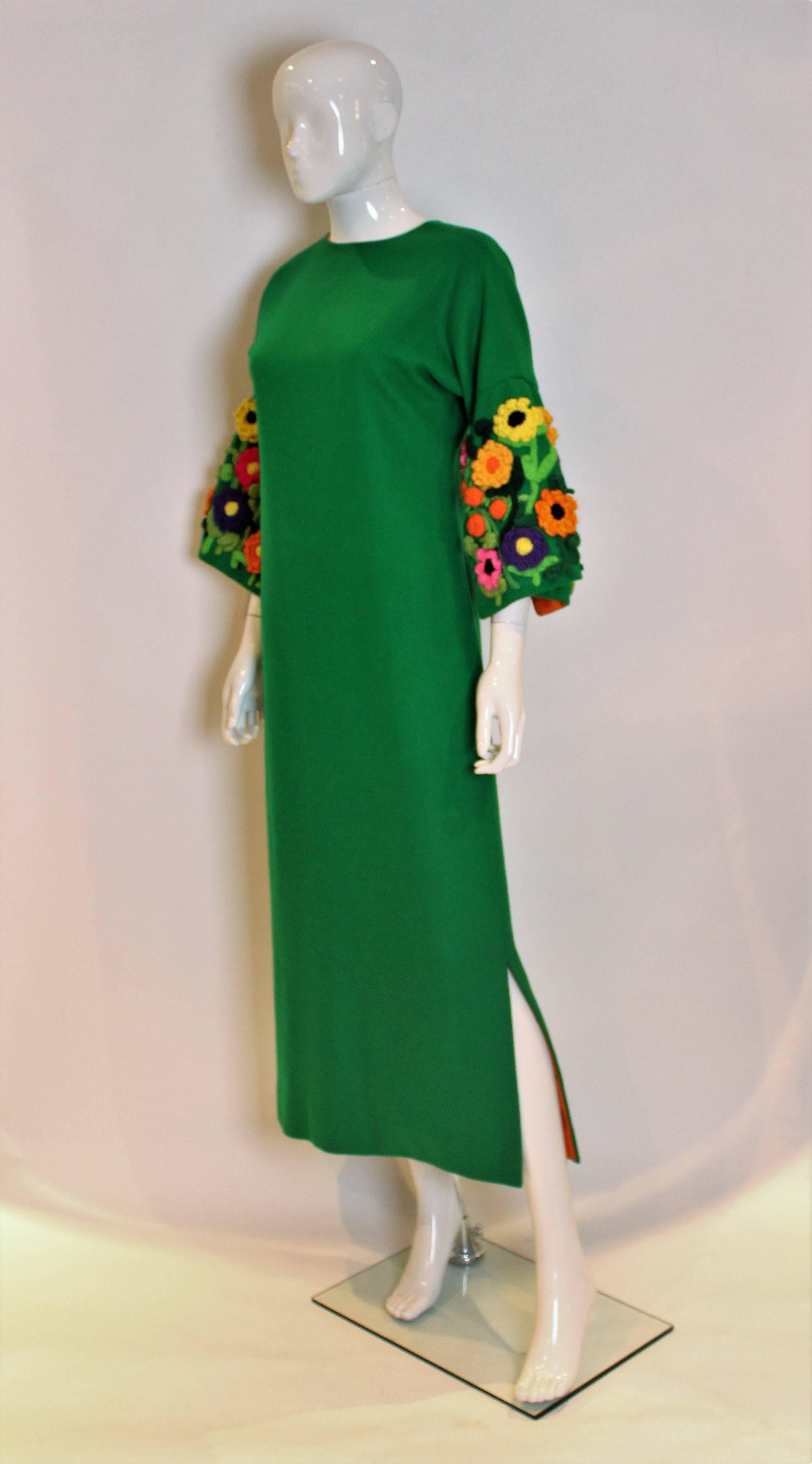 A striking shift dress from the 1960s . The outer dress is a bright green wool, and the lining is a vibrant orange.. The sleeves are a great shape with stunning floral decoration. The dress has a round neck, central back zip and 12 1/2
