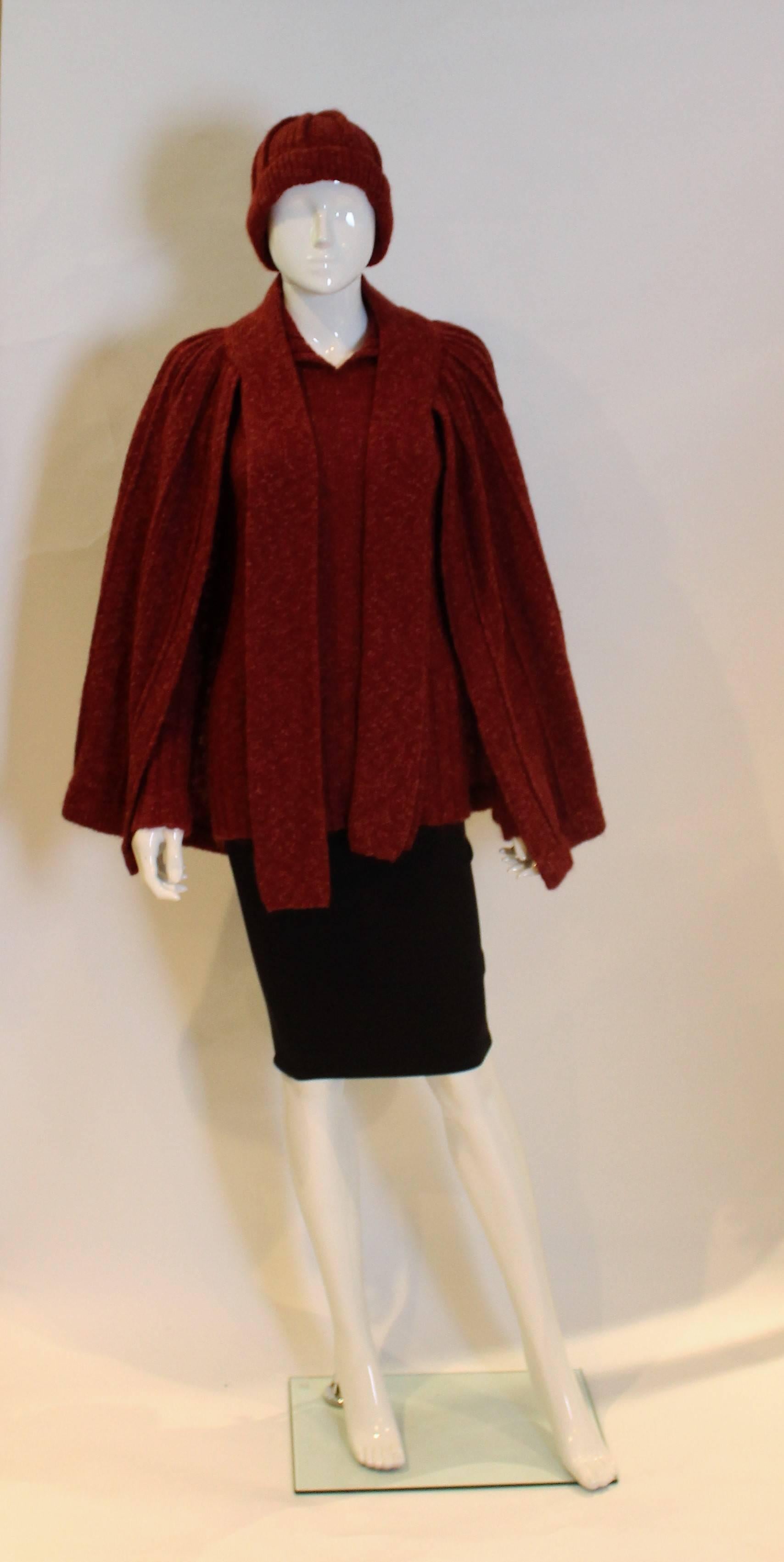 A great outfit for Fall. In a plum colour wool, by famous Italian firm Missoni,this outfit comprises a jumper with attractive wide ribbing on the cuffs and hem.A cape with ties at the neck and a woolly hat.
