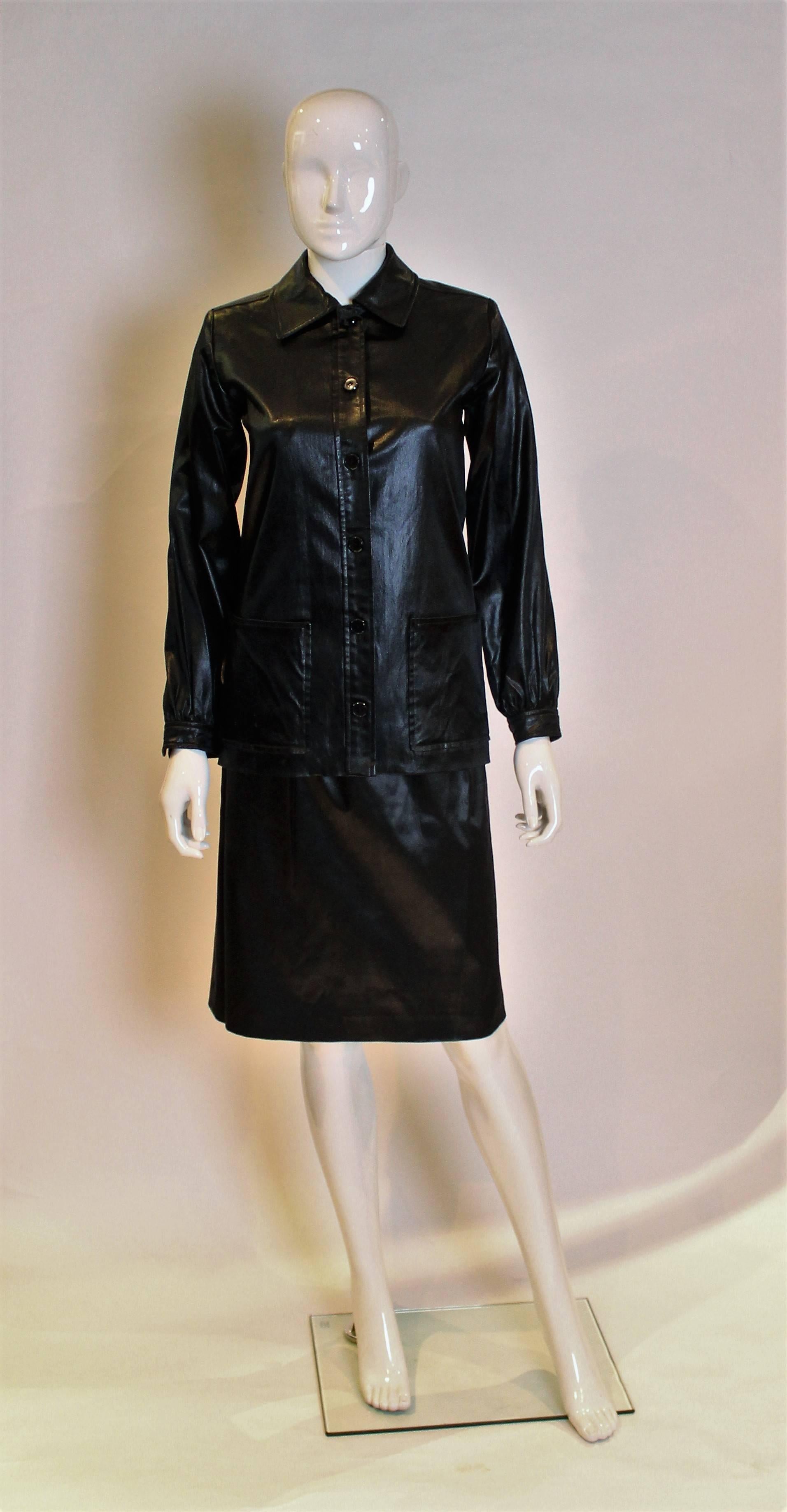 A skirt suit by Yves Saint Laurent in a 'wet look' fabric. 
The jacket fastens with 6 buttons on the front, has single button cuffs and two large pockets.The skirt has an elasticated  waist . Both size 36

Jacket : bust 34'', length 26 ''
Skirt: