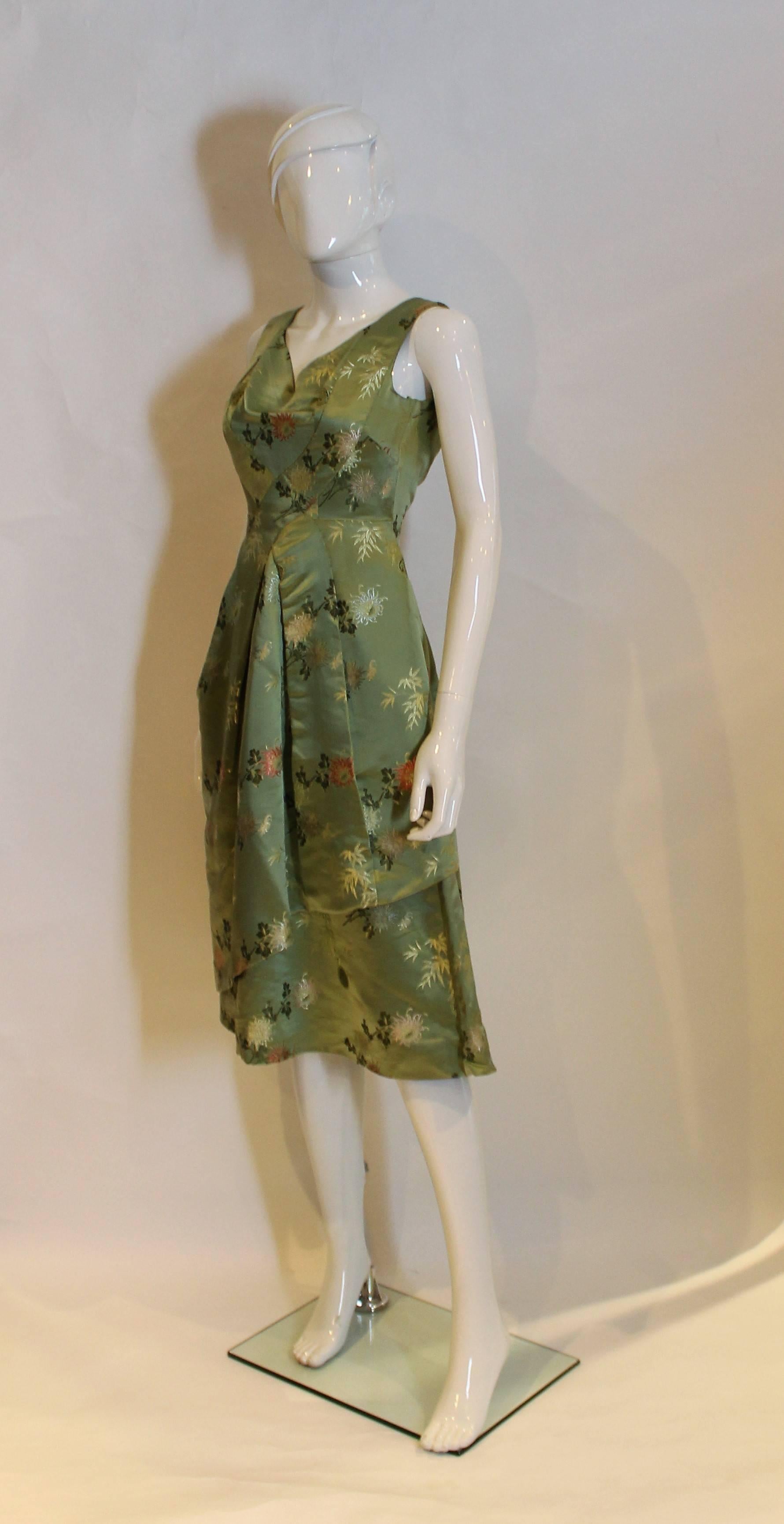 A great dress in a soft green colour silk with floral design. The dress has a v neck line and back ,and central back zip.