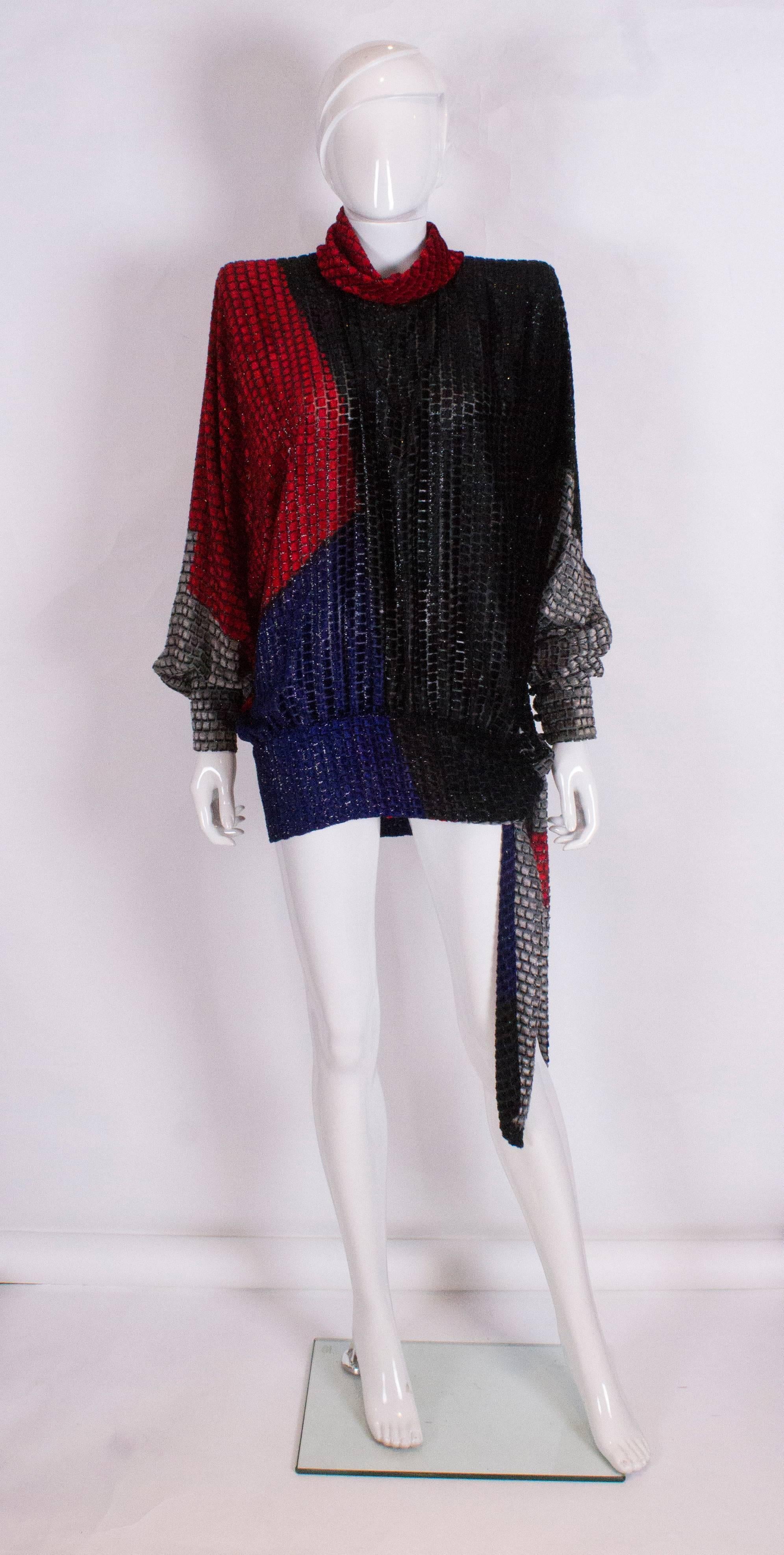 A great top by Italian designer Andrea Odicini. The top is a wonderful mix of red, blue, grey and black square with a black background. The top has a tie at waist leval, a button neck and 4 button wide cuffs. The top should be worn loose, but can
