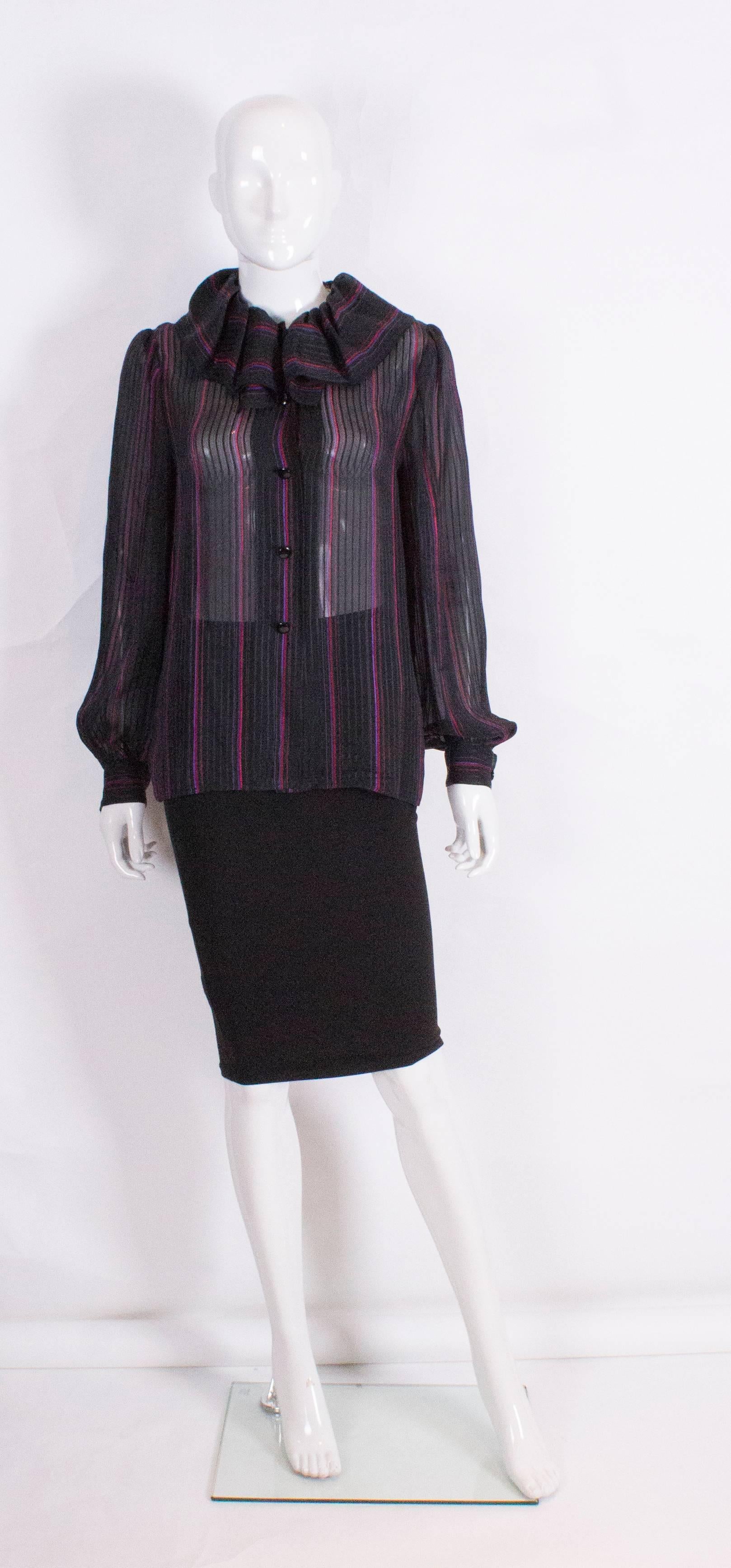 A chic blouse by Givenchy Boutique. The blouse  has a black background with pink and purple stripes, a frill collar, a central 5 button opening and one button on each cuff.