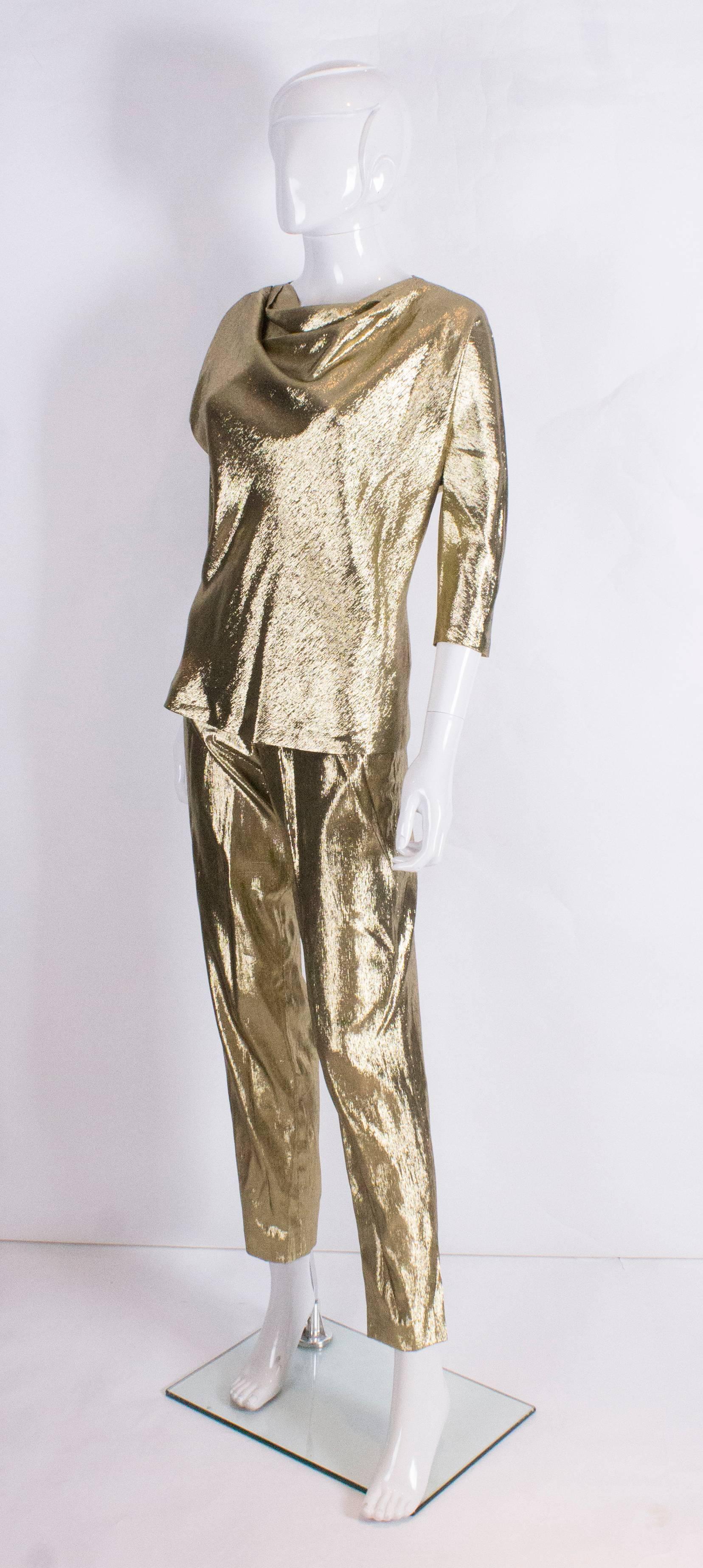 A glorious gold pant suit by British designer Rich Bitch. The top has a cowl like neck, and is bias cut with elbow length sleeves and the trousers are tapered like cigarette pants.The fabric is 90% silk , 10% metal.
Top bust 33'', length 2