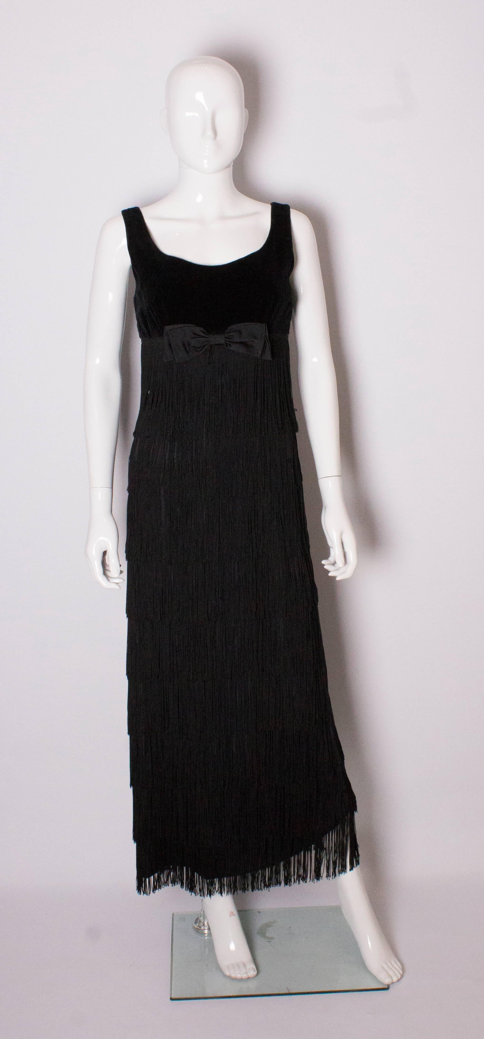A stunning gown by Alquer of London. The dress has a deep scoop neckline front and back with a central back zip. The bodice is black velvet with a bow and below are 9 rows of fringing.This makes a wonderful woosh as you walk.  There is a 4 1/2 ''