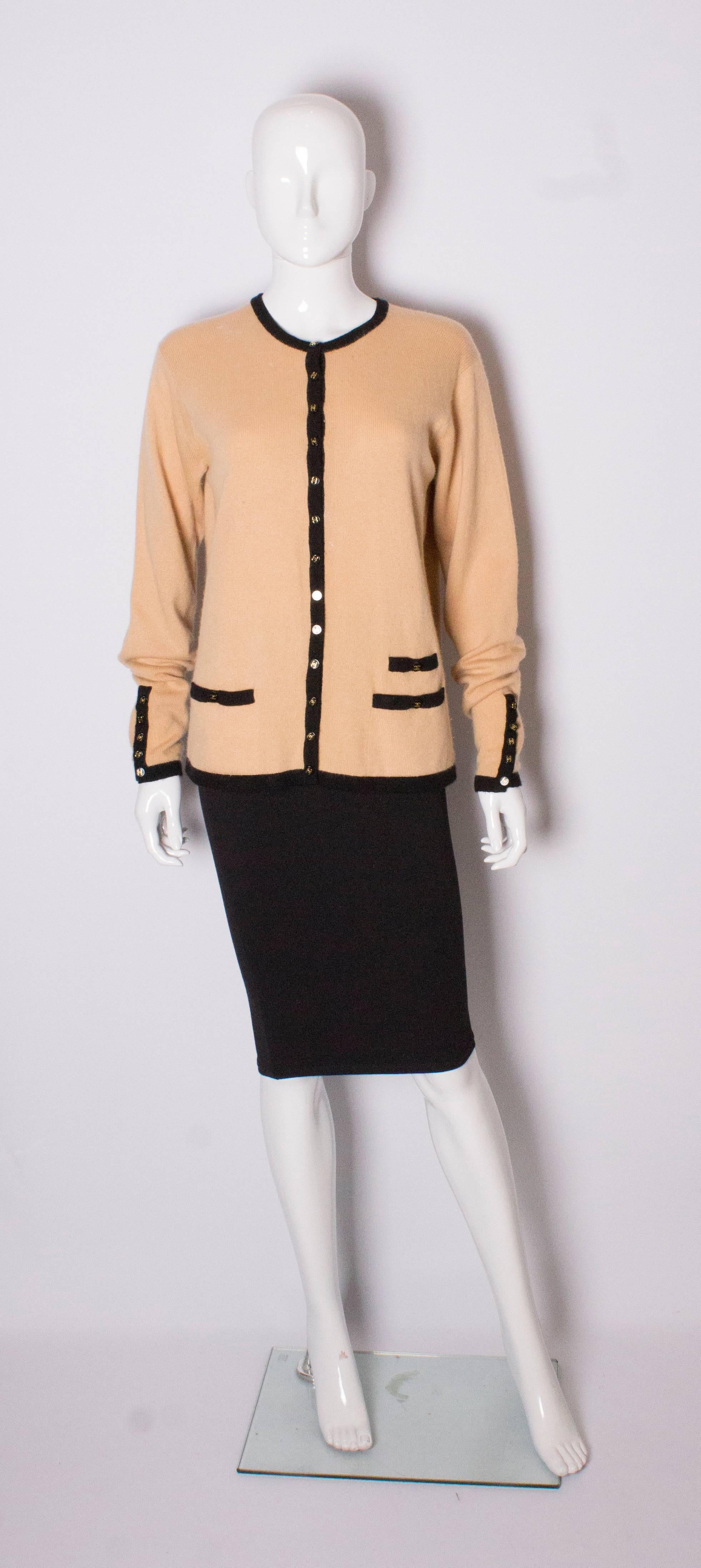 Chic cashmere cardigan by Chanel. The cardigan is a caramel colour with black trim around the neck, hem and cuffs. It as all the original black Chanel buttons.