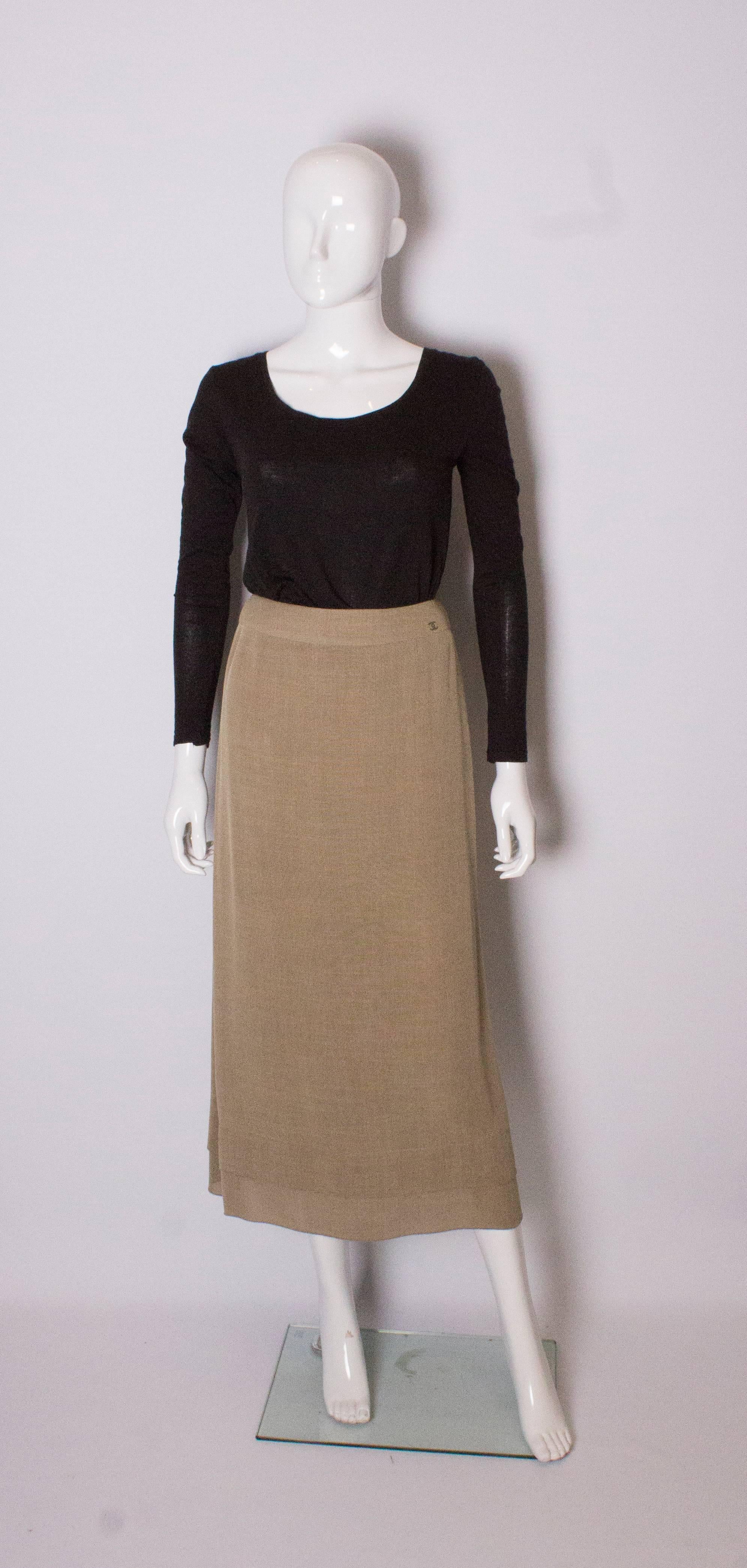 A chic biscuit colour skirt by Chanel . The skirt is slightly gathered at the waist, lined in silk , has  a double hem/layer at the hem a back zip and 16 '' slit at the back.