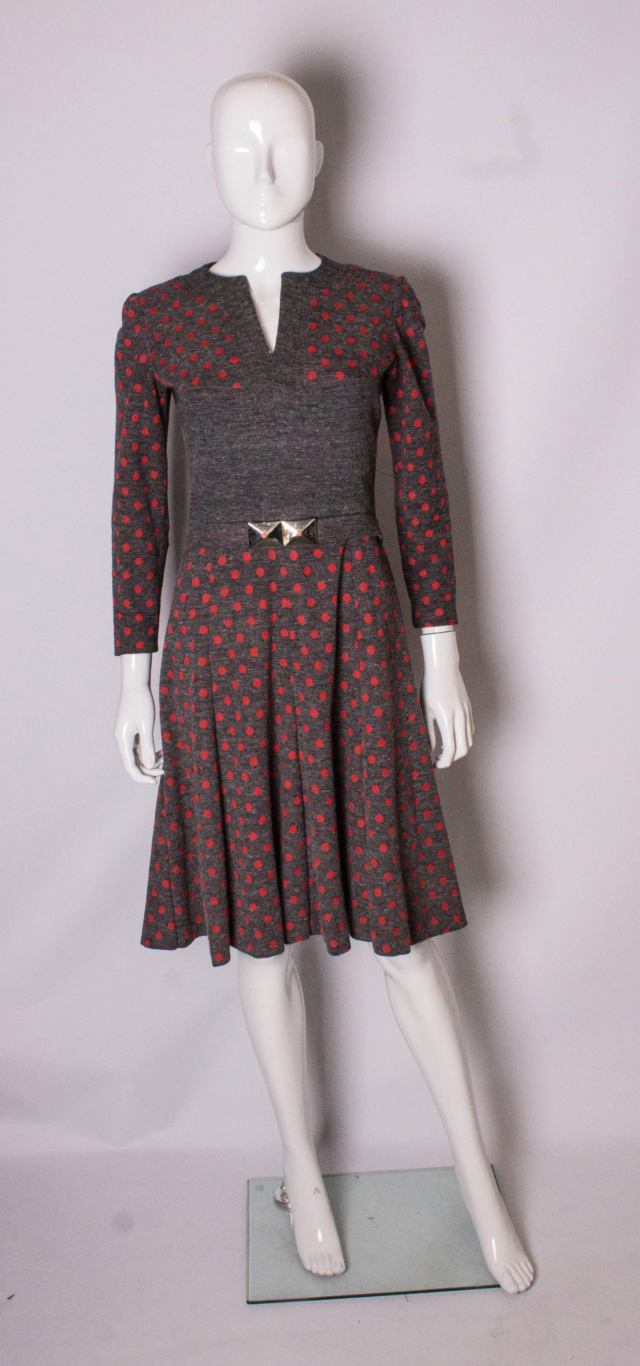 A chic and easy to wear dress by Hardy Amies. The dress has a v neckline, central back zip,plain fabric over the bust area and is fully lined. The skirt is flared and it has a self fabric belt with two buckles.