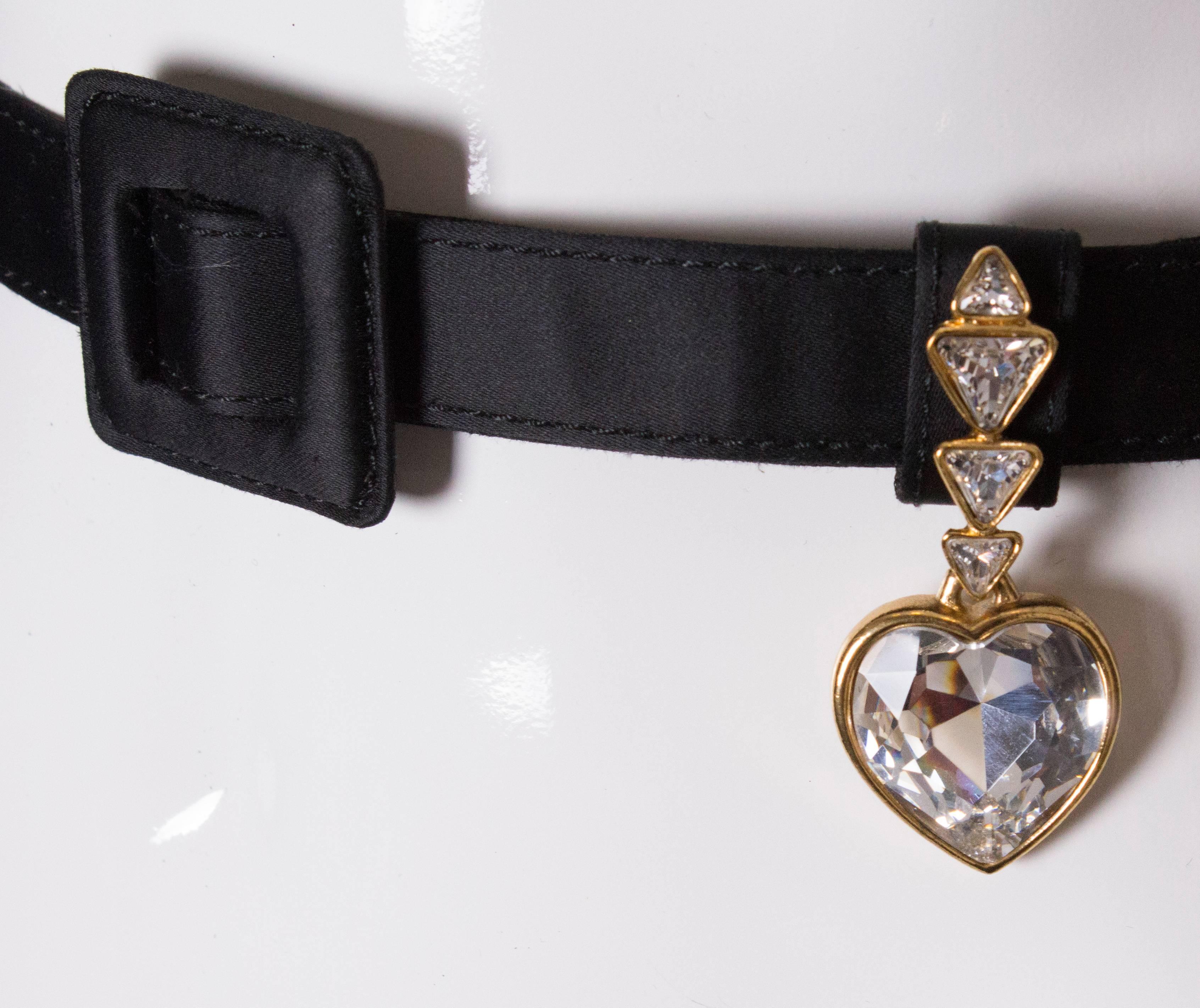 A super chic black satin belt by Yves Saint Laurent . The belt has a crystal covered belt hoop, and decorative piece. It has no holes and so can be altered to your size. It has a 5cm square buckle , and the following stamped on the inside. YSL 3764