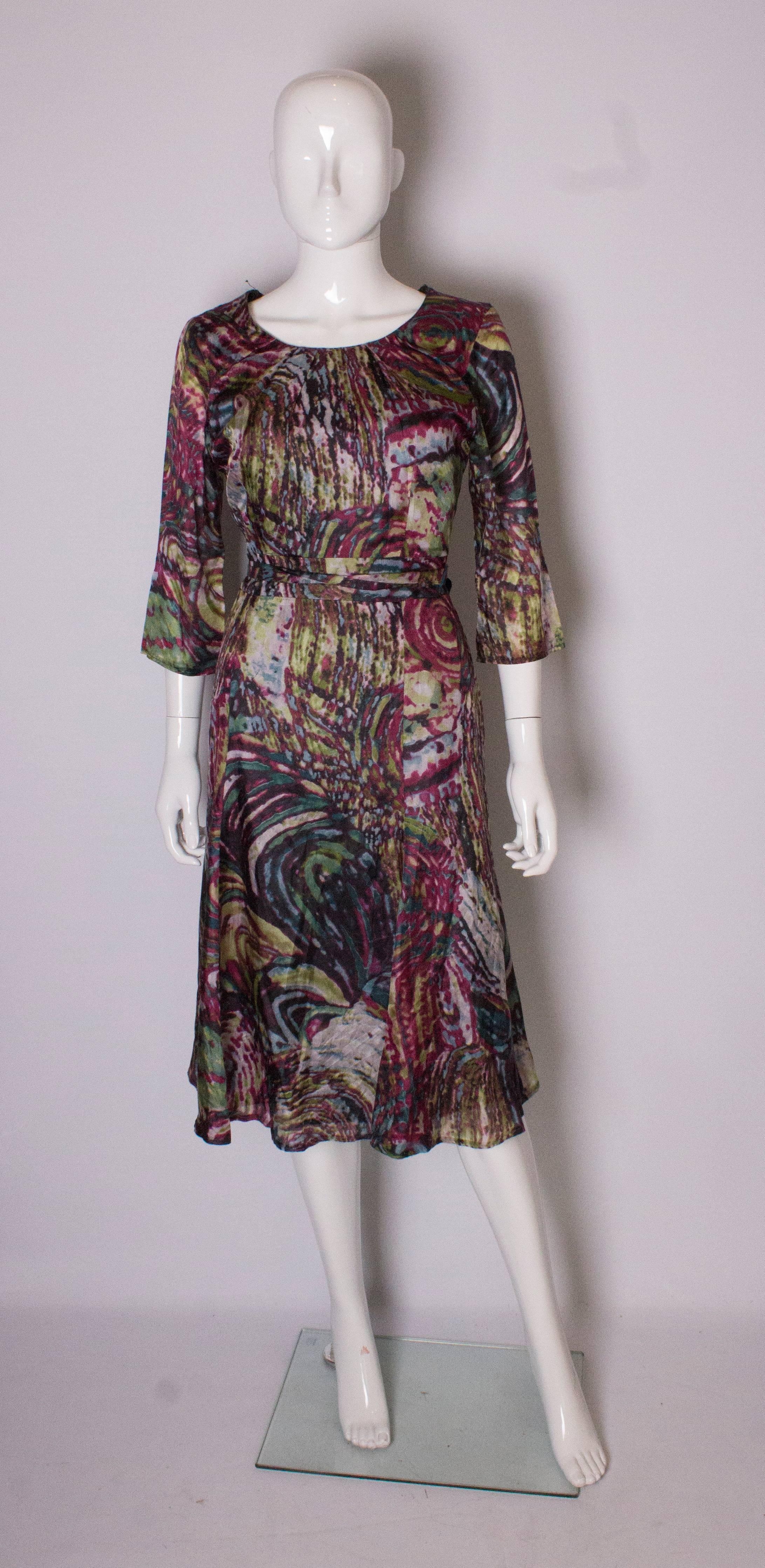  A great silk day dress in a wonderful print of burgundy , green and cream. The dress a boat neckine, side zip, elbow length sleeves and 2'' self fabric belt. 