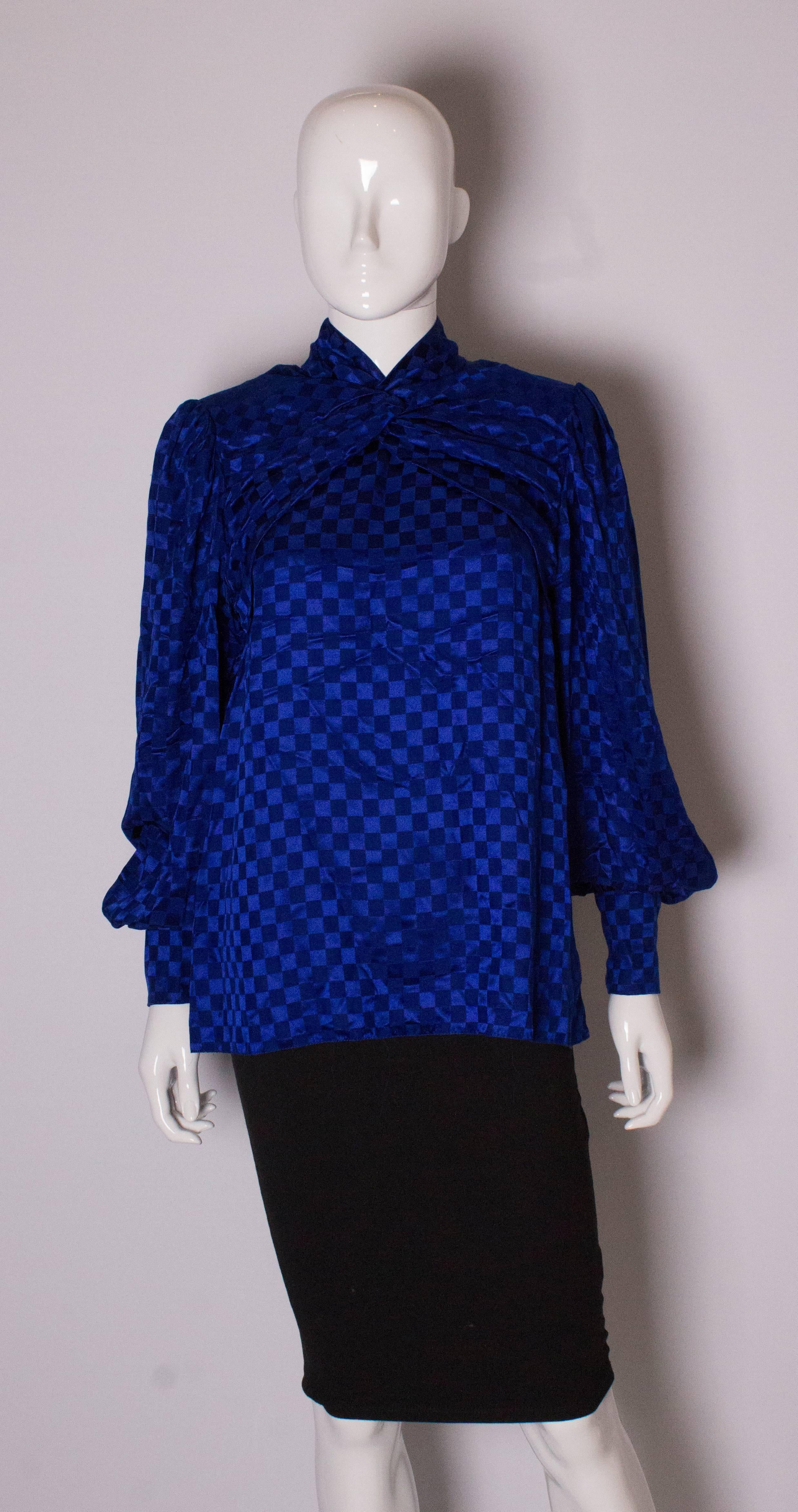 A stunning blue silk blouse by British designer Donald Campbell. The blouse has gathering over the bust,a zip back and hree button cuffs.