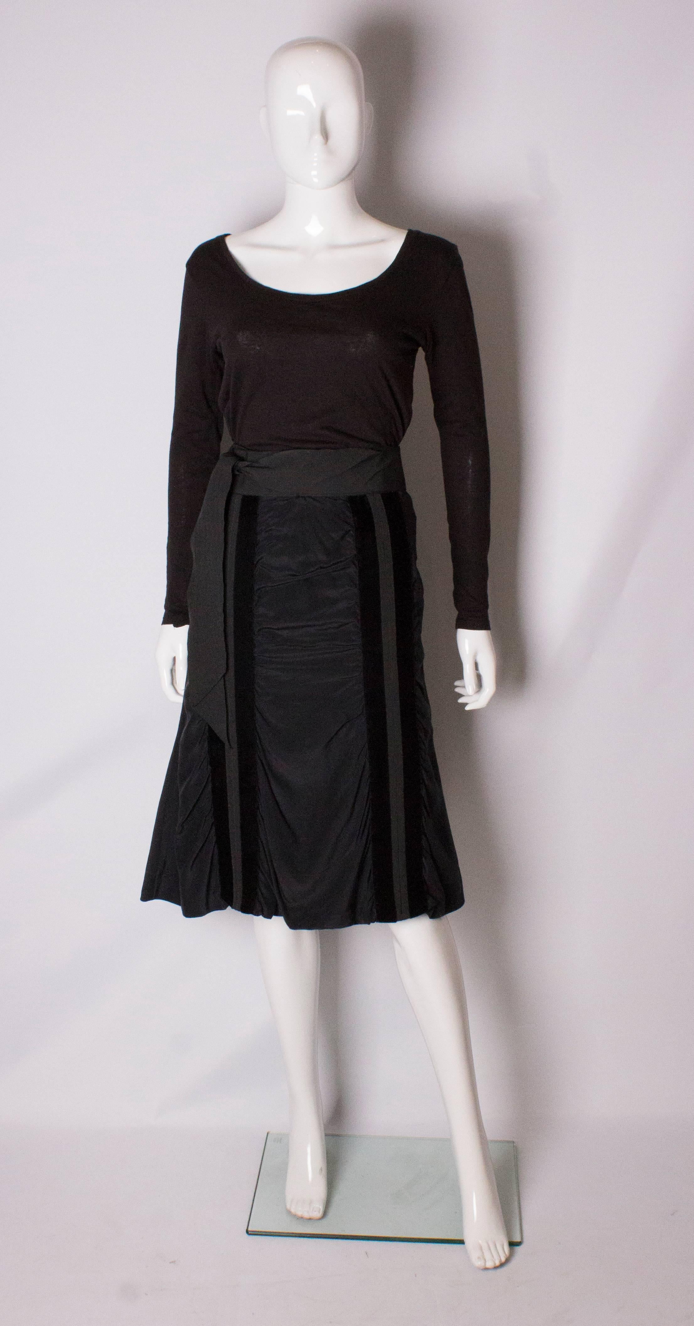 A super silk skirt by Yves Saint Laurent Rive Gauche line. The skirt is made of silk , and is lined in silk. It has a central back zip and vertical velvet stripe on the front and back, with a grossgrain self tie belt. It has never been worn.