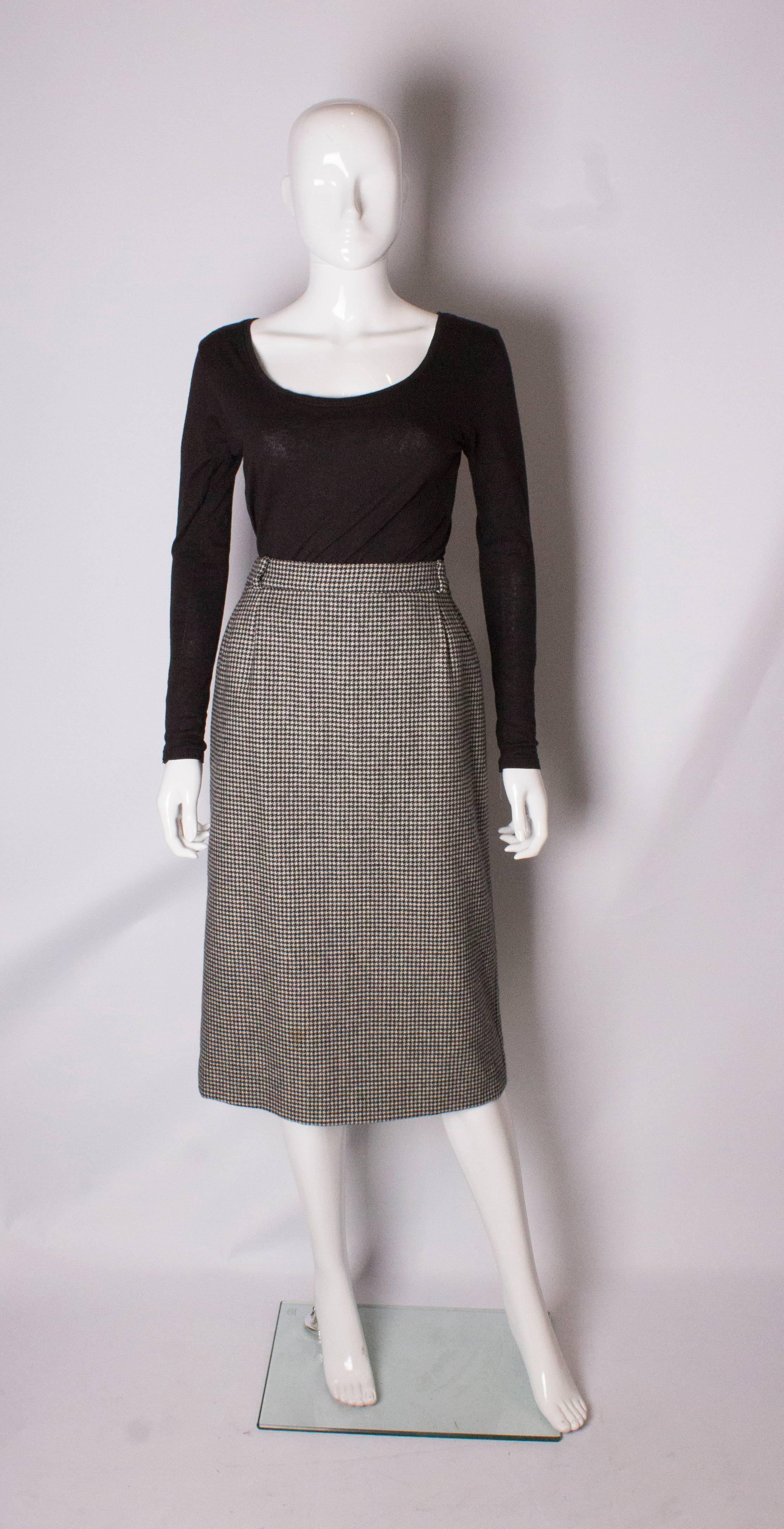 A chic vintage skirt by Celine. In a black and white hounds tooth wool, the skirt is fully lined, has a central back zip , belt hoops, and a 9'' slit at the back.