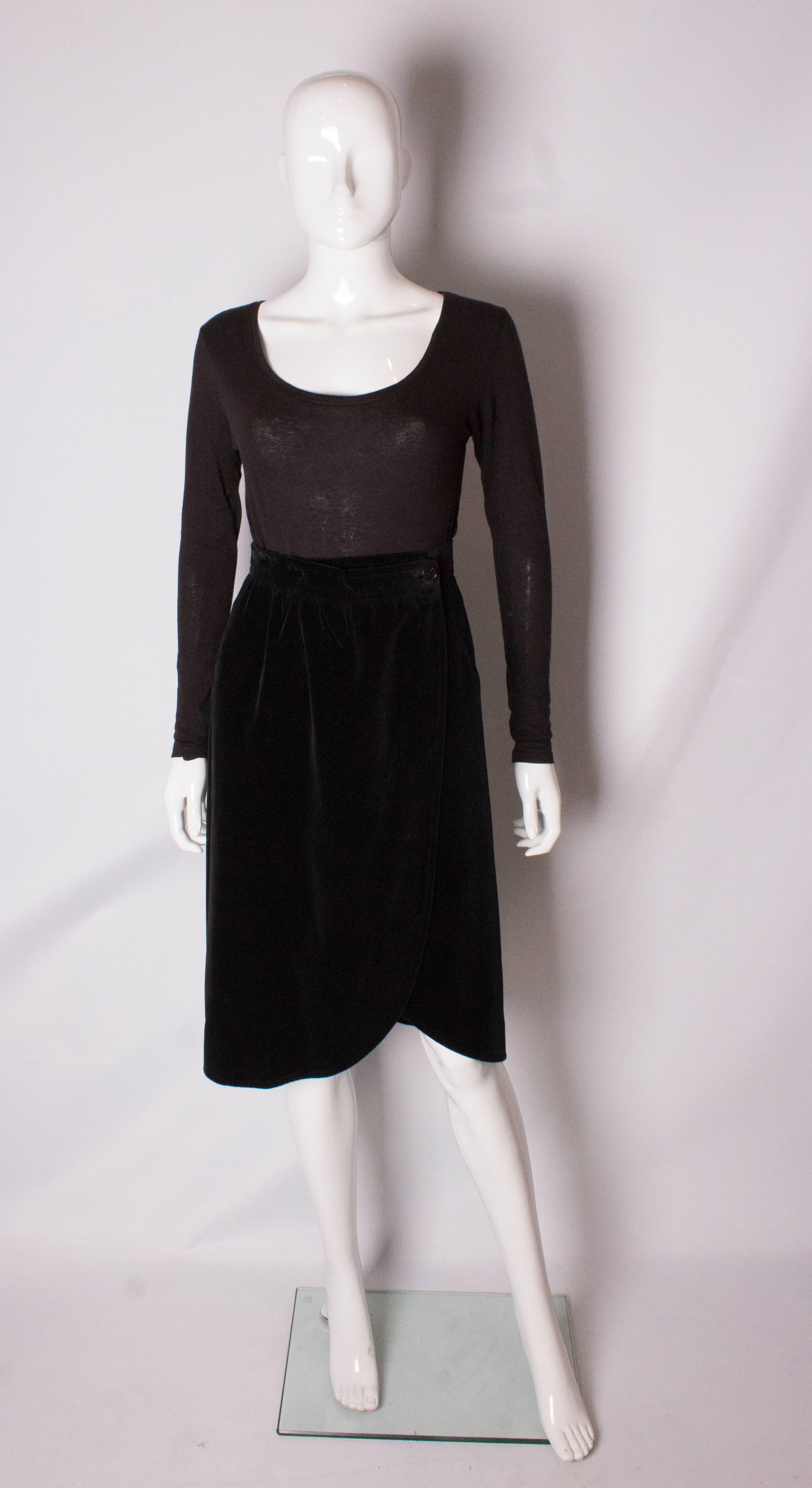 A chic black velvet wrap around skirt by Yves Saint Laurent , Variation line. The skirt is fully lined and has a pocket on the right hand side.
